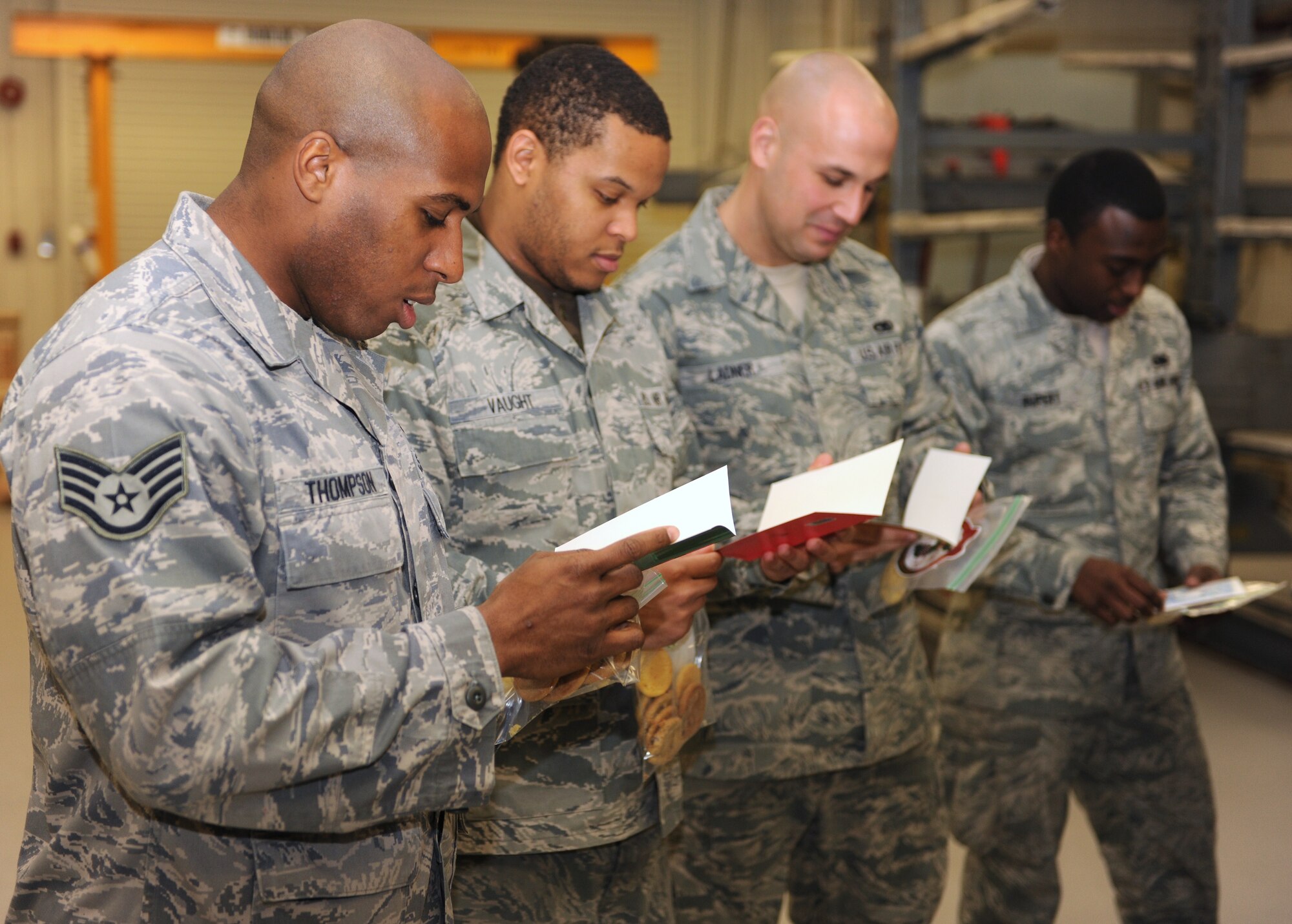 KUNSAN AIR BASE, Republic of Korea -- 8th Maintenance Squadron Airmen read Christmas cards donated by the Osan Air Base, Republic of Korea, officer’s spouses’ club here Dec. 17, 2010.  Col. John Costa, 7th Air Force chief of staff, Chief Master Sgt. Tom Baker, 7th Air Force command chief, and their spouses visited the Wolf Pack for Cookie Crunch, where donated cookies were delivered to Airmen all over base at their work centers. (U.S. Air Force photo/Senior Airman Ciara Wymbs)  