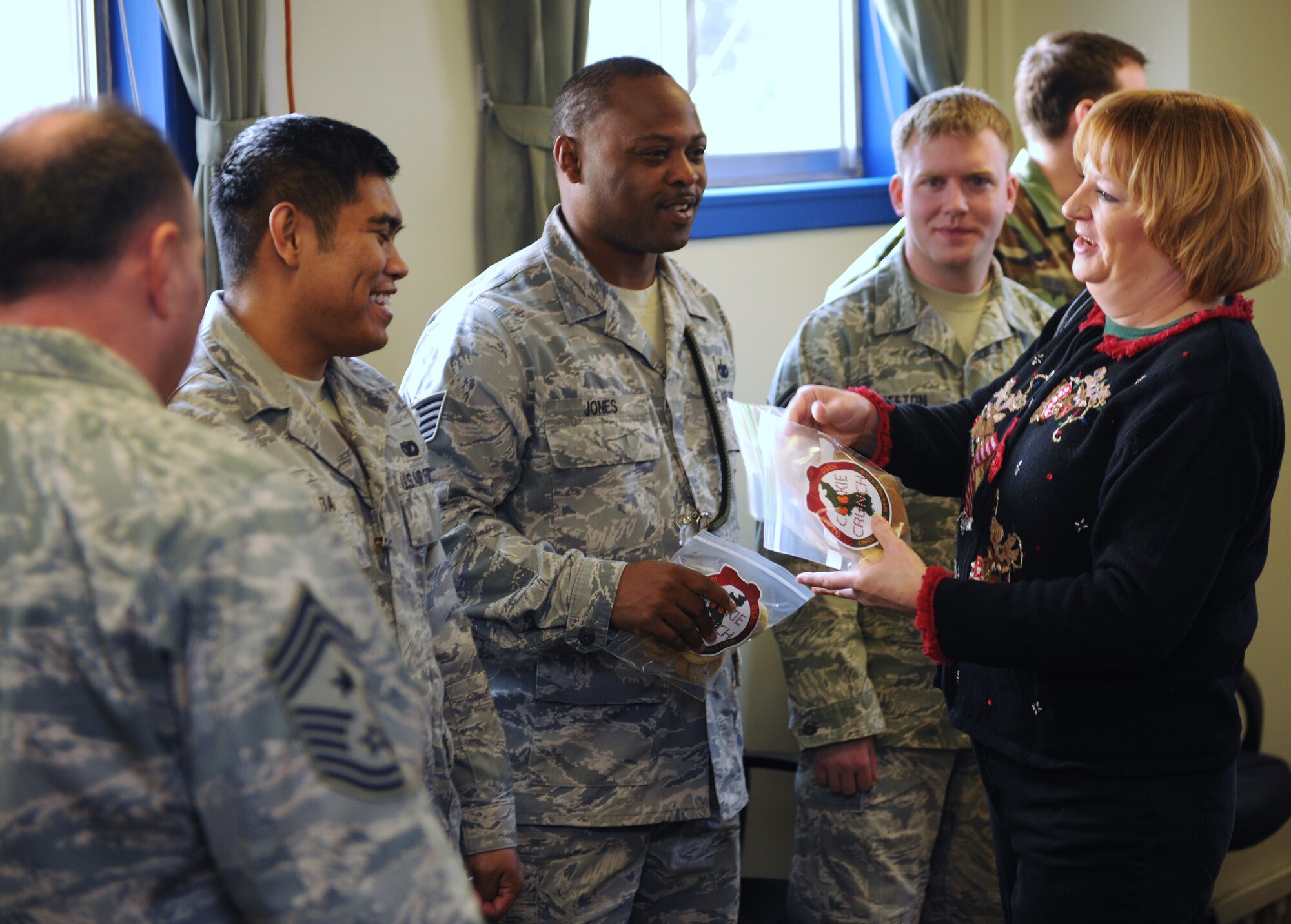KUNSAN AIR BASE, Republic of Korea -- Kris Costa, wife of Col. John Costa, 7th Air Force chief of staff, hands cookies out to Wolf Pack defenders here Dec. 17, 2010. Colonel Costa, Chief Master Sgt. Tom Baker, 7th Air Force command chief, and their spouses visited the Wolf Pack for Cookie Crunch, where donated cookies were delivered to Airmen all over base at their work centers. (U.S. Air Force photo/Senior Airman Ciara Wymbs)  