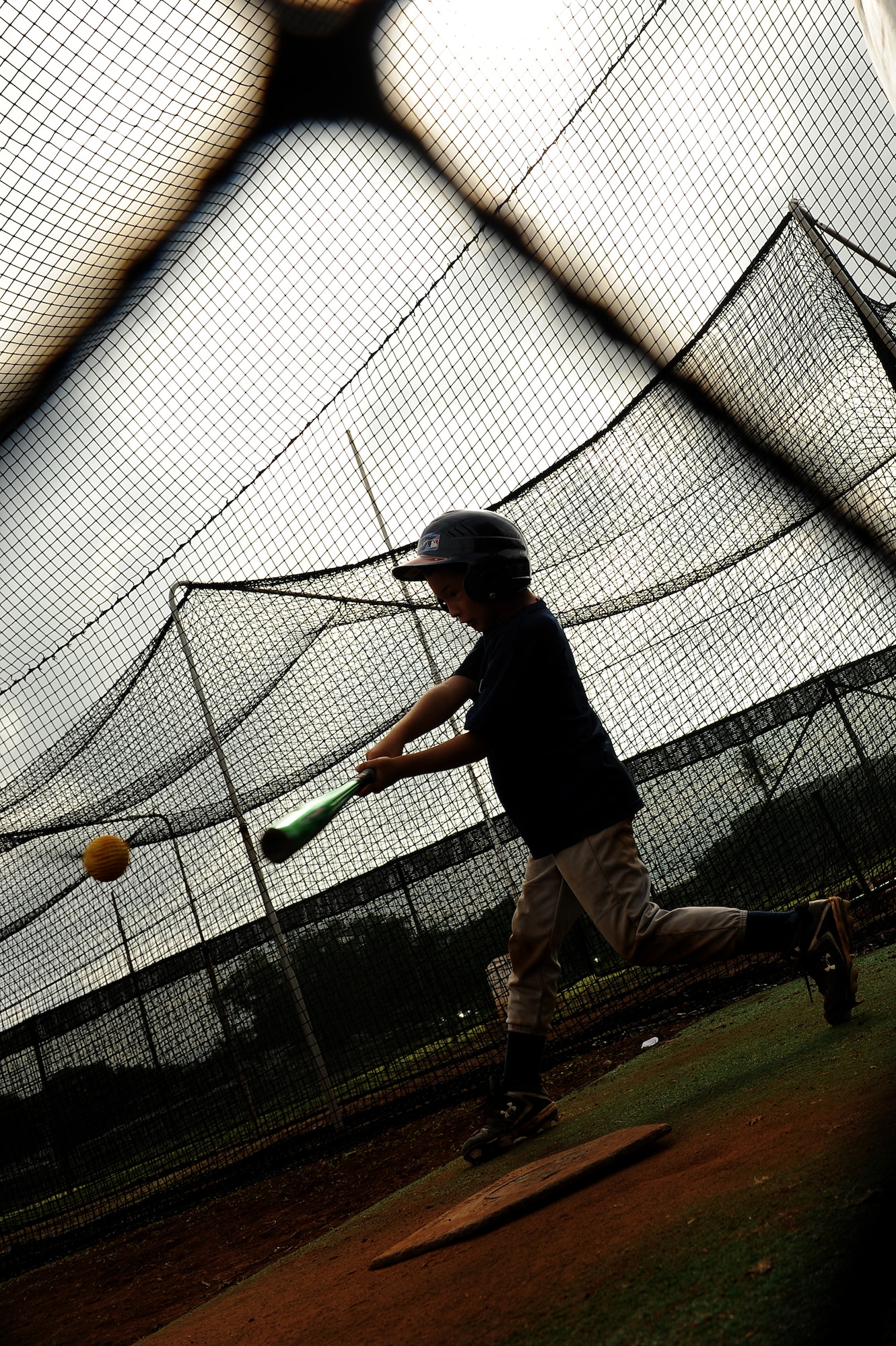 Omar Valle, 9, takes a few cuts at baseballs in the batting cage during the Friends of Hickam baseball clinic Dec. 18. Hickam and Pearl Harbor children were taught baseball fundamentals by University of Hawaii and Hawaii Pacific University coaches and players duringthe event. The baseball clinic is the first of an annually planned event for the Friends of Hickam. (U.S. Air Force photo/Staff Sgt. Mike Meares)