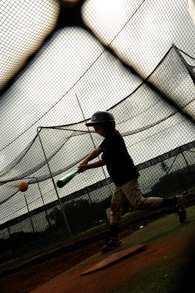 Omar Valle, 9, takes a few cuts at baseballs in the batting cage during the Friends of Hickam baseball clinic Dec. 18. Hickam and Pearl Harbor children were taught baseball fundamentals by University of Hawaii and Hawaii Pacific University coaches and players duringthe event. The baseball clinic is the first of an annually planned event for the Friends of Hickam. (U.S. Air Force photo/Staff Sgt. Mike Meares)