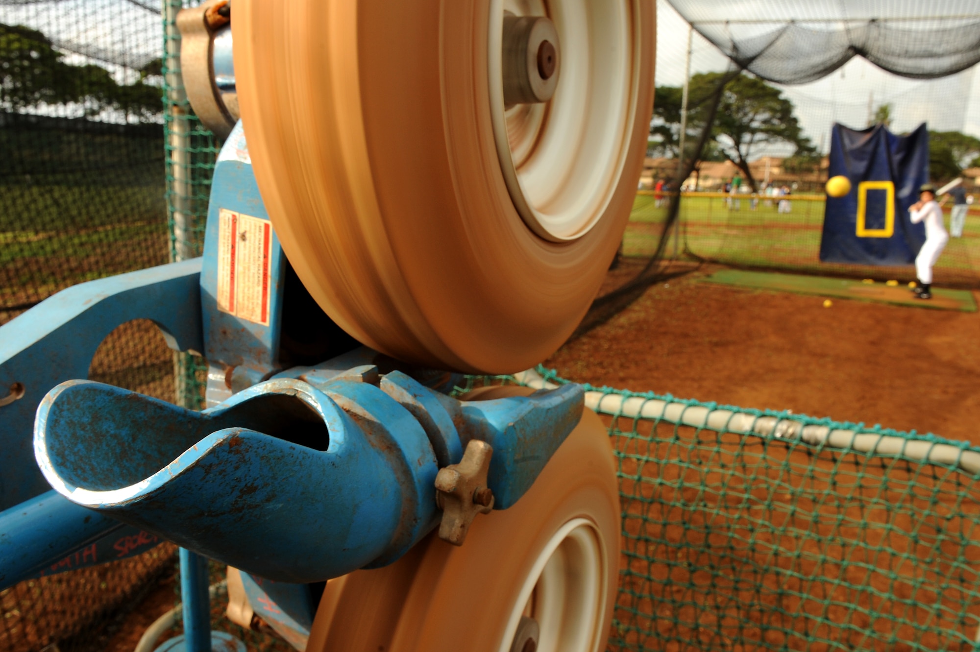 A batter takes a few pitches in the batting cages during the Friends of Hickam baseball clinic Dec. 18. Hickam and Pearl Harbor children were taught baseball fundamentals by University of Hawaii and Hawaii Pacific University coaches and players duringthe event. The baseball clinic is the first of an annually planned event for the Friends of Hickam. (U.S. Air Force photo/Staff Sgt. Mike Meares)