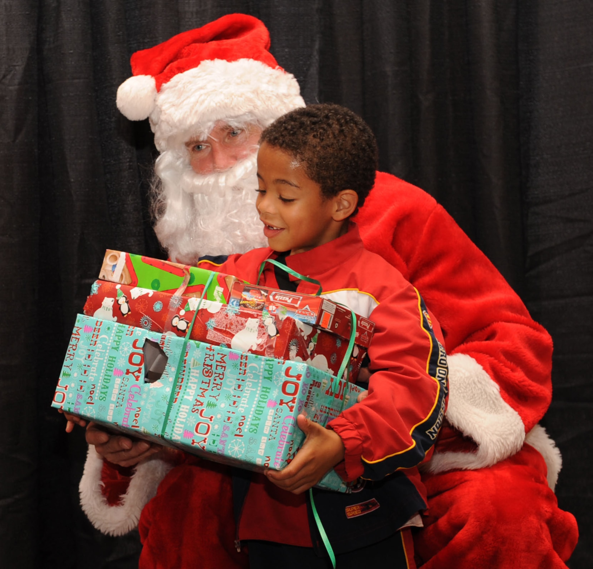 Jacob Thrasher, 6, receives presents from Santa Claus during the Santa's in Blue event at the Bossier City Civic Center in Bossier City, La., Dec. 18. Santa's in Blue is a program sponsored by the Air Force Sergeants Association and Barksdale Top Three to provide gifts for more than 400 children in foster care. (U.S. Air Force photo/Airman 1st Class Sean Martin)(Released)
