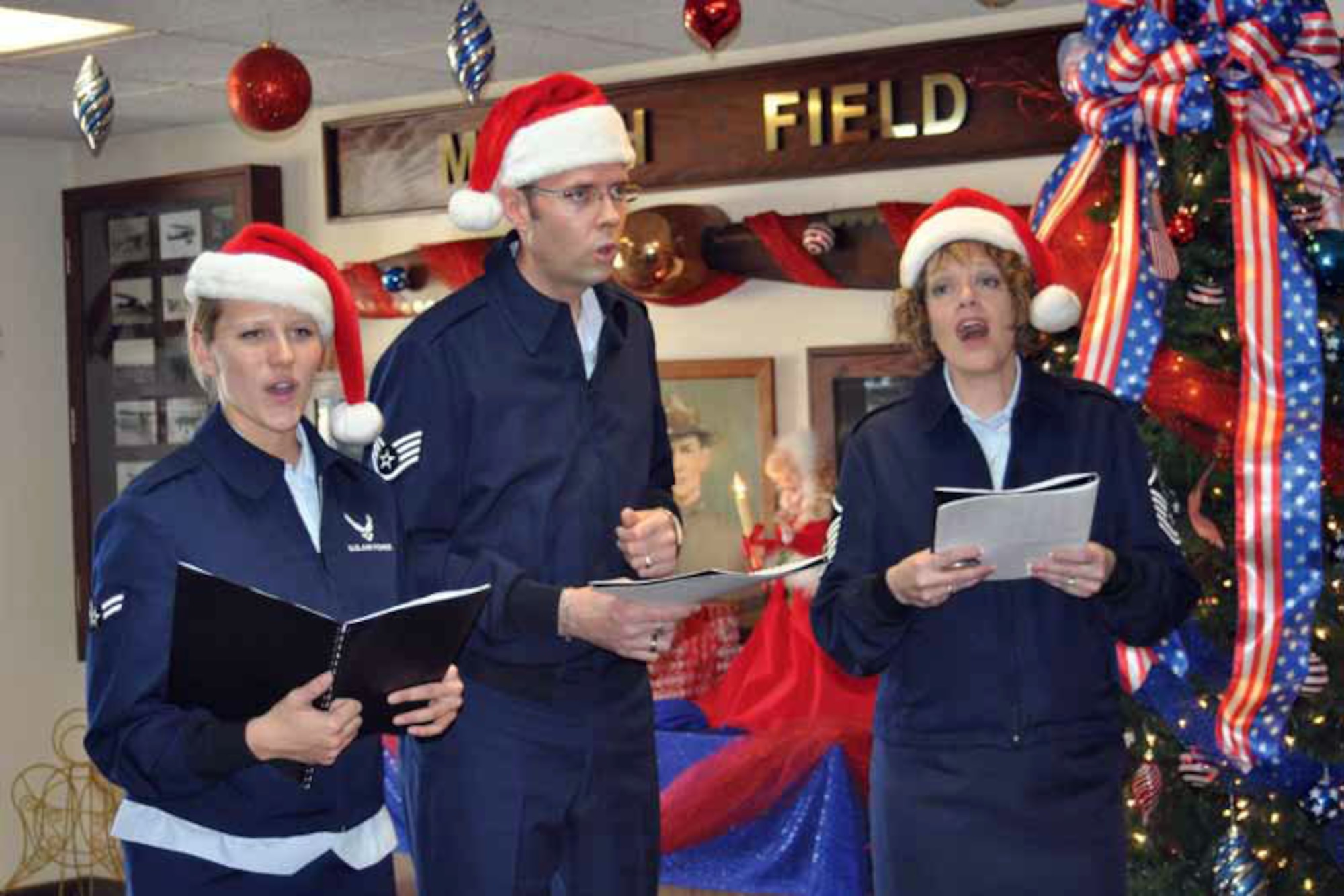 Airman 1st Class Megan Hokaj, Staff Sgt. Geoffrey Fisher and Master Sgt. Amy Lukens-Malone sing holiday carols to the staff at the 452nd Air Mobility Wing headquarters  building on Monday. The carolers are members of the Air Force Band of the Golden West at Travis Air Force Base, Calif. They sang at 10 locations at March and will be singing at other Southern California Air Forces Bases during the rest of the week. (U.S. Air Force photo by Valerie Palacios)