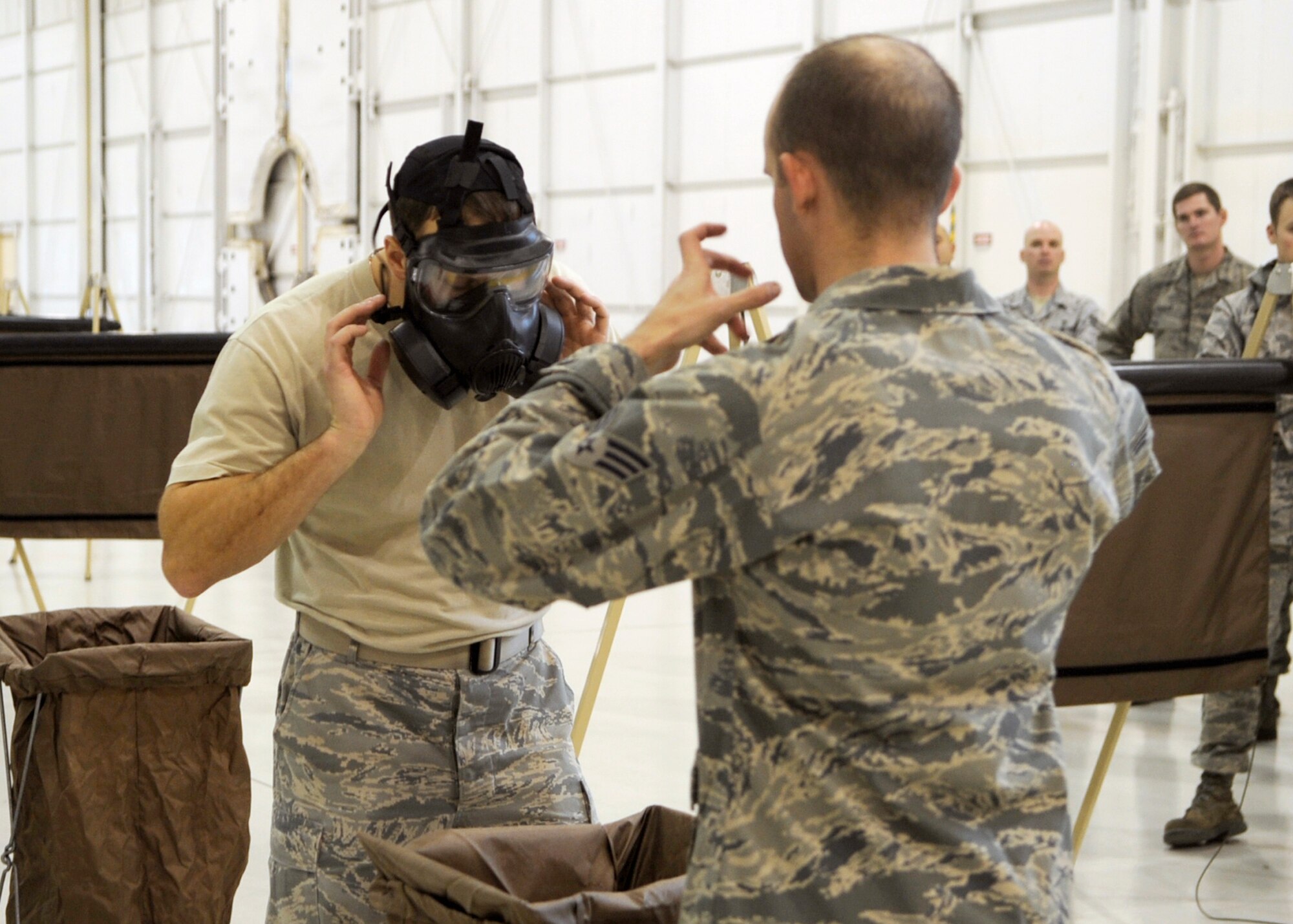 Senior Airman David Kandziolka demonstrates how to properly remove his simulated contaminated gas mask to Staff Sgt. Troy Zimmerman Dec. 13, 2010, at Mountain Home Air Force Base, Idaho, during an ability to survive and operate rodeo. The ATSO rodeo helped increase the critical real-world and phase II ATSO skills through combined academic and practical stations. Airman Kandziolka and Sergeant Zimmerman are assigned to the 366th Civil Engineer Squadron. (U.S. Air force photo/Senior Airman Angelina Drake)