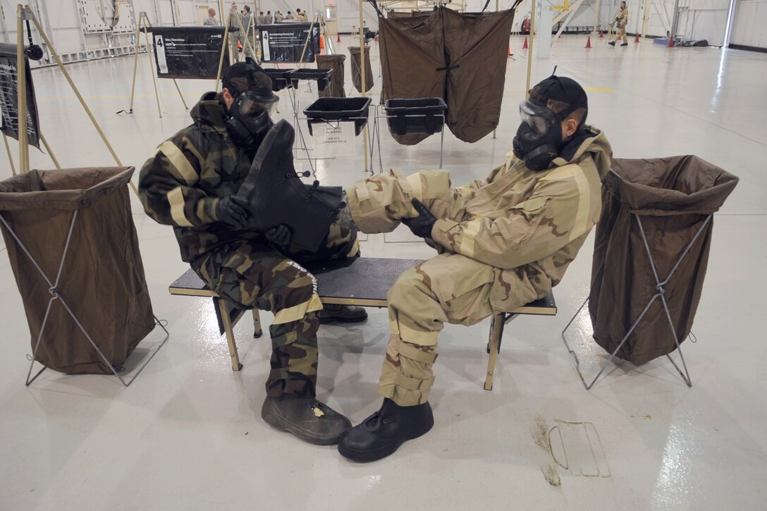 Airman Sabrina Crawford and Staff Sgt. Troy Zimmerman assist each other in the removal of simulated contaminated gear Dec. 13, 2010, at Mountain Home Air Force Base, Idaho, during an ability to survive and operate rodeo. Airman Crawford is assigned to the 366th Medical Group, and Sergeant Zimmerman is assigned to the 366th Civil Engineer Squadron. (U.S. Air force photo/Senior Airman Angelina Drake)