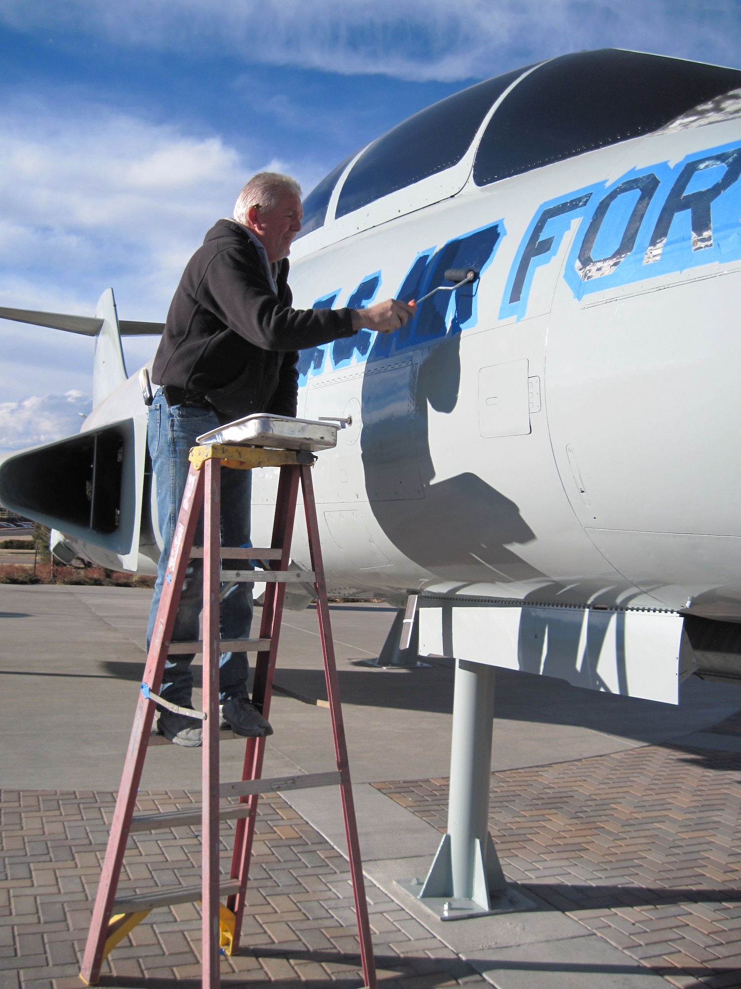 An employee from Enviro-Tech, a Georgia-based company that specializes in restoring, treating and painting static display aircraft, paints the U.S. Air Force name across the forward fuselage of the F-101 “Voodoo” aircraft  Dec. 15 on Peterson Air Force Base. The work is part of a $76,000 restoration project of several aircraft at the Peterson Air and Space Museum funded North American Aerospace Defense Command and U.S. Northern Command. (U.S. Air Force photo/Jeff Nash)