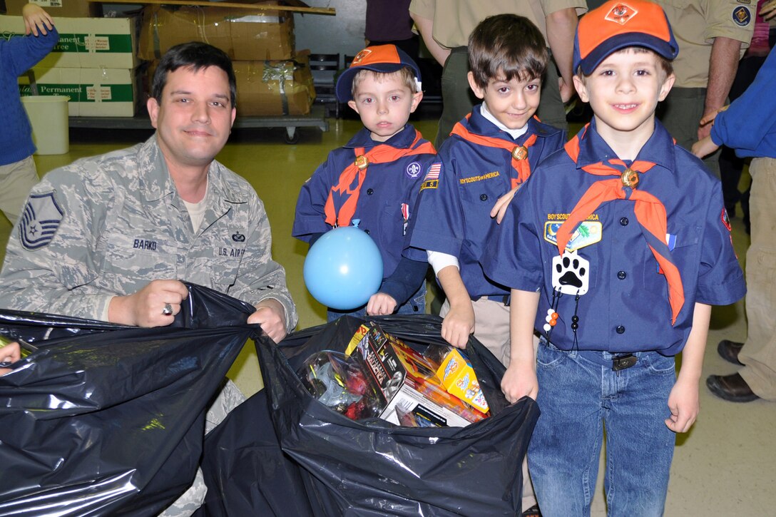 WARREN, Ohio -- Air Force Reserve Master Sgt. Bob Barko Jr., 910th Airlift Wing superintendent of public affairs, kneels next to three Cub Scouts and two bags full of gifts at Blessed Sacrament Elemnetary School here, Dec. 16. Sergeant Barko, based at nearby Youngstown Air Reserve Station, Ohio is accepting the toys from Greater Western Reserve Council Cub Scout Pack 101 on behalf of the air station for the U.S. Marine Corps Reserve Toys for Tots Program. The mission of Toys for Tots is to collect new, unwrapped toys during October, November and December each year, and distribute those toys as Christmas gifts to needy children in the community in which the campaign is conducted. Air Force Reserve, Navy Reserve as well as civilian personnel and the Marine Corps Reservists assigned to YARS team up to bring the Toys for Tots program to the residents of Youngstown, Warren and surrounding areas for the past several years. Courtesy photo by Deana Creatura.