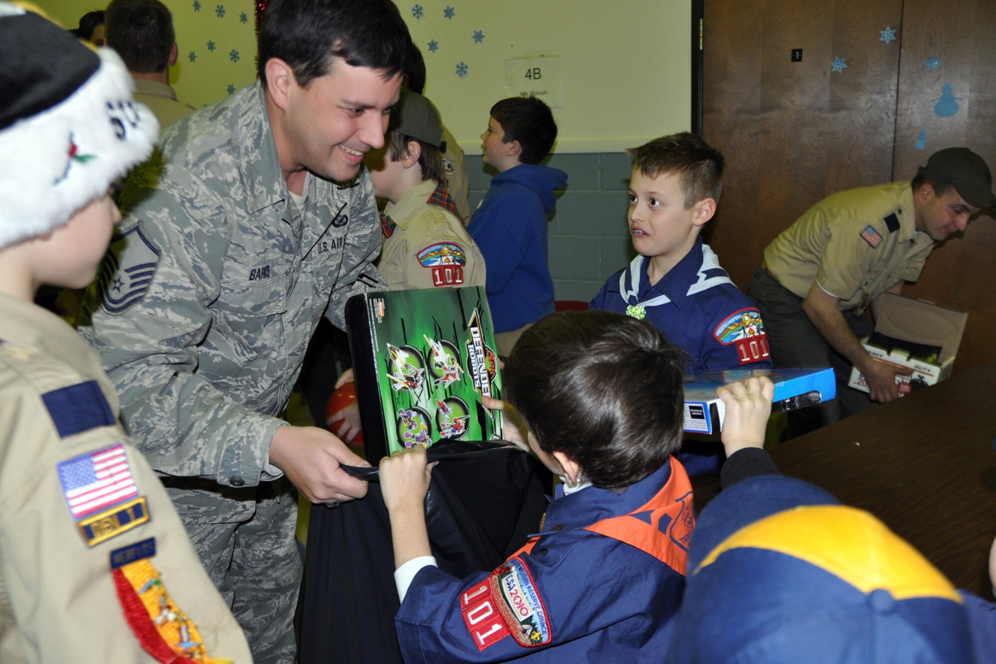 WARREN, Ohio -- Air Force Reserve Master Sgt. Bob Barko Jr., 910th Airlift Wing superintendent of public affairs, holds a bag while a Cub Scout places a toy in it at Blessed Sacrament Elemnetary School here, Dec. 16. Sergeant Barko, based at nearby Youngstown Air Reserve Station, Ohio is accepting the toys from Greater Western Reserve Council Cub Scout Pack 101 on behalf of the air station for the U.S. Marine Corps Reserve Toys for Tots Program. The mission of Toys for Tots is to collect new, unwrapped toys during October, November and December each year, and distribute those toys as Christmas gifts to needy children in the community in which the campaign is conducted. Air Force Reserve, Navy Reserve as well as civilian personnel and the Marine Corps Reservists assigned to YARS team up to bring the Toys for Tots program to the residents of Youngstown, Warren and surrounding areas for the past several years. Courtesy photo by Deana Creatura. 