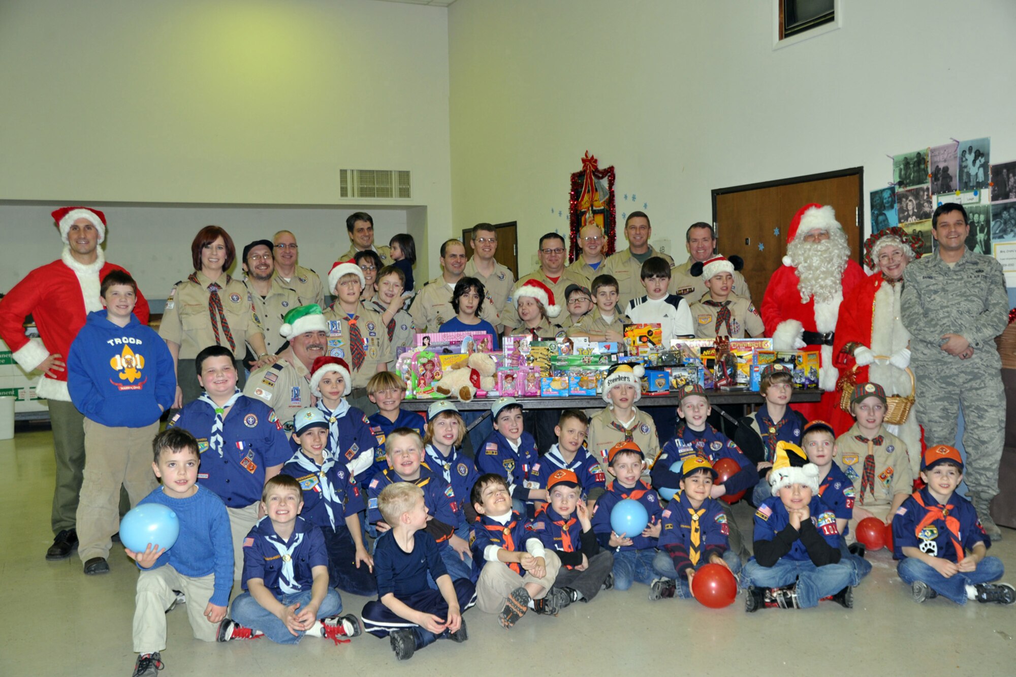 WARREN, Ohio -- Air Force Reserve Master Sgt. Bob Barko Jr., 910th Airlift Wing superintendent of public affairs, stands with a group of Cub scouts, pack leaders, Santa Claus and Mrs. Claus around a table full of gifts at Blessed Sacrament Elemnetary School here, Dec. 16. Sergeant Barko, based at nearby Youngstown Air Reserve Station, Ohio is accepting the toys from Greater Western Reserve Council Cub Scout Pack 101 on behalf of the air station for the U.S. Marine Corps Reserve Toys for Tots Program. The mission of Toys for Tots is to collect new, unwrapped toys during October, November and December each year, and distribute those toys as Christmas gifts to needy children in the community in which the campaign is conducted. Air Force Reserve, Navy Reserve as well as civilian personnel and the Marine Corps Reservists assigned to YARS team up to bring the Toys for Tots program to the residents of Youngstown, Warren and surrounding areas for the past several years. Courtesy photo by Deana Creatura
