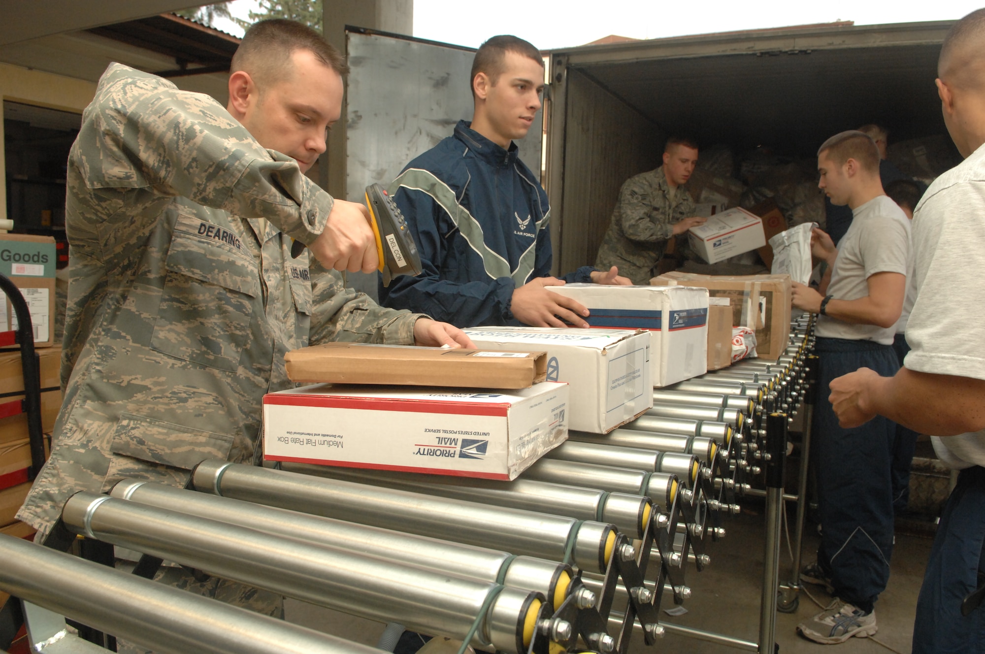 Tech. Sgt Eric Dearing, the post master for the Official Document Center, scans mail while volunteers unload mail from the truck, Dec. 13, at Incirlik Air Base Turkey. The ODC is asking for volunteers to expedite the delivery of mail to the Incirlik community. (U.S. Air Force photo by Tech. Sgt. Valda Wilson/Released)
