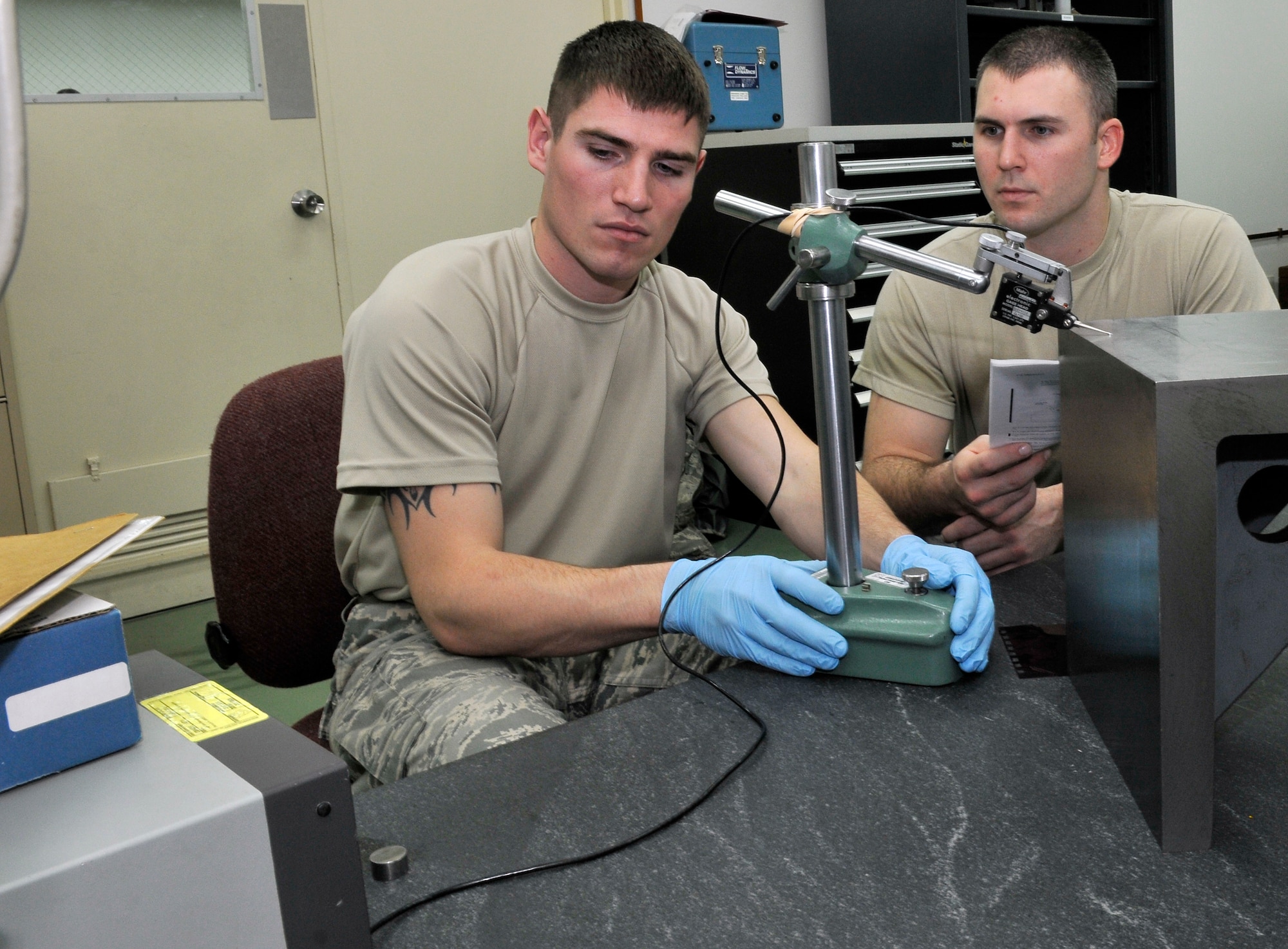 U.S. Air Force Senior Airmen Kyle Meister, moves a height gauging head across a right-angle iron as Staff Sgt. Brian Brawley trains him how to read the electronic amplifier Dec. 20, 2010 Misawa Air Base, Japan. The electronic amplifier that PMEL uses can measure deviations in metal as small as .05 micro inches. Both Airmen are assigned to the 35th Maintenance Squadron Precision Measurement Equipment Laboratory. (U.S. Air Force photo by Tech. Sgt. Phillip Butterfield/Released) 