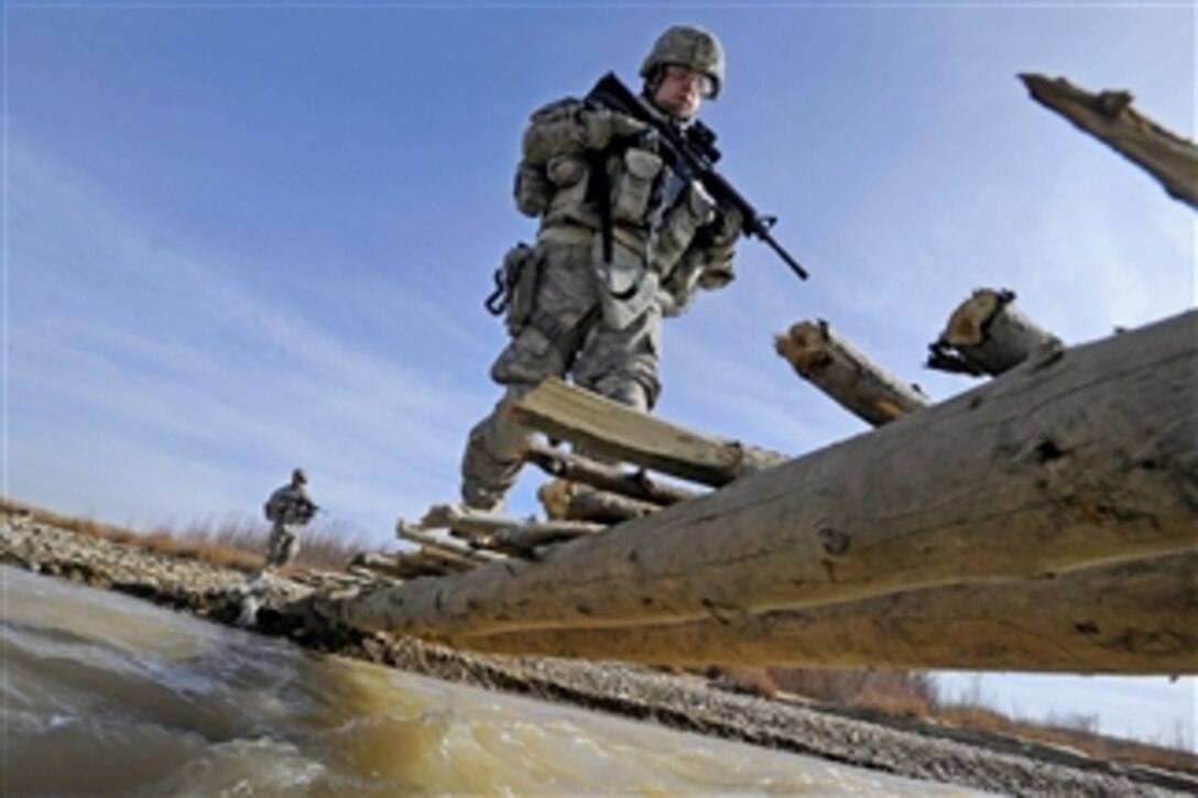 U.S. Army Spc. Erik Martin uses a footbridge to cross a river during a mission to Khwazi village, Afghanistan, on Dec. 14, 2010.  Martin, a member of Provincial Reconstruction Team Zabul, visited the village to survey a site for a future well project.  