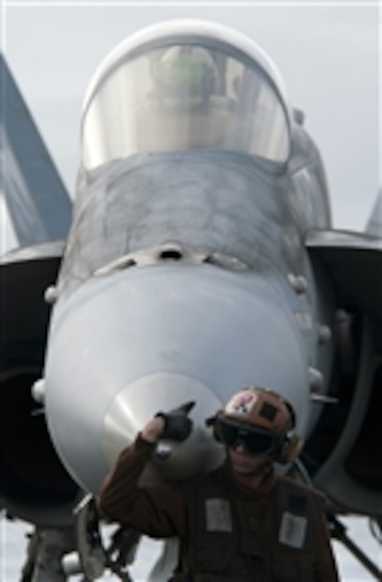 Airman Tyler Signer, a plane captain assigned to Strike Fighter Squadron 113, waits for the launch of an F/A-18C Hornet after completing start up and pre-flight checks with the pilot aboard the aircraft carrier USS Carl Vinson (CVN 70) underway in the Pacific Ocean on Dec. 17, 2010.  The Carl Vinson and Carrier Air Wing 17 are on a three-week composite training unit exercise to be followed by a deployment to the western Pacific Ocean.  