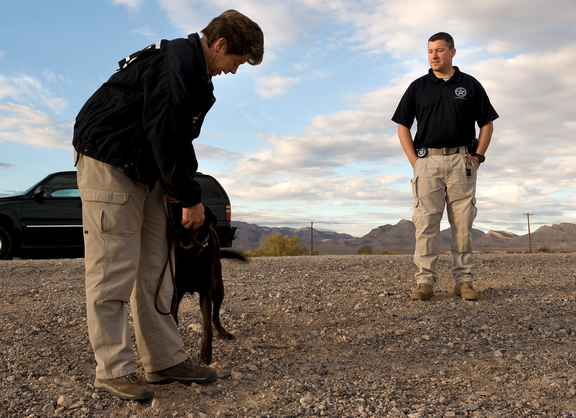 NELLIS AIR FORCE BASE, Nev.-- Jon A. Minnich, a U.S. Marshals Service explosive detection canine handler, discusses different explosive odor combinations with Lauren Marakas, senior special agent canine handler from the Bureau of Alcohol, Tobacco, Firearms, and Explosives, while petting Ruthie, an explosives detection canine, during a joint explosive detection training exercise Dec. 16. Military working dog handlers from the 99th Security Forces Squadron worked with 25 canine teams from the Las Vegas area. (U.S. Air Force photo by Senior Airman Brett Clashman)