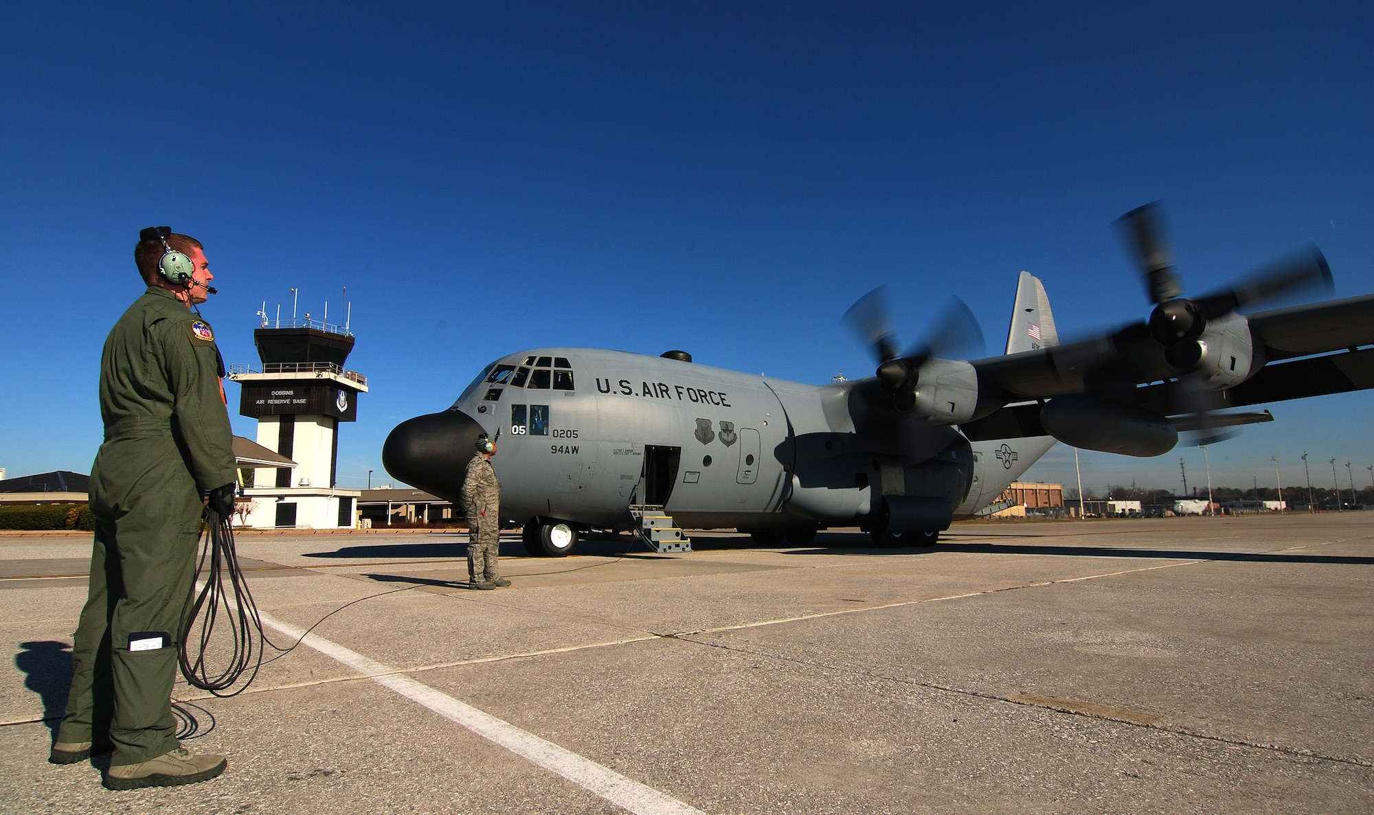 Senior Airman Brett Grove a loadmaster with the 700th Airlift Squadron communicates with the rest of the C-130H2 Hercules aircrew as he monitors the start of the number one engine on the outboard pylon at Dobbins Air Reserve Base, Ga., Dec 20.    Tech. Sgt. Tim Mansion of the 94th Aircraft Maintenance Flight and the dedicated crew chief for this aircraft stands by to monitor the engine start.  The Hercules belongs to the 94th Airlift Wing at Dobbins.   (U.S. Air Force photo/ Brad Fallin)