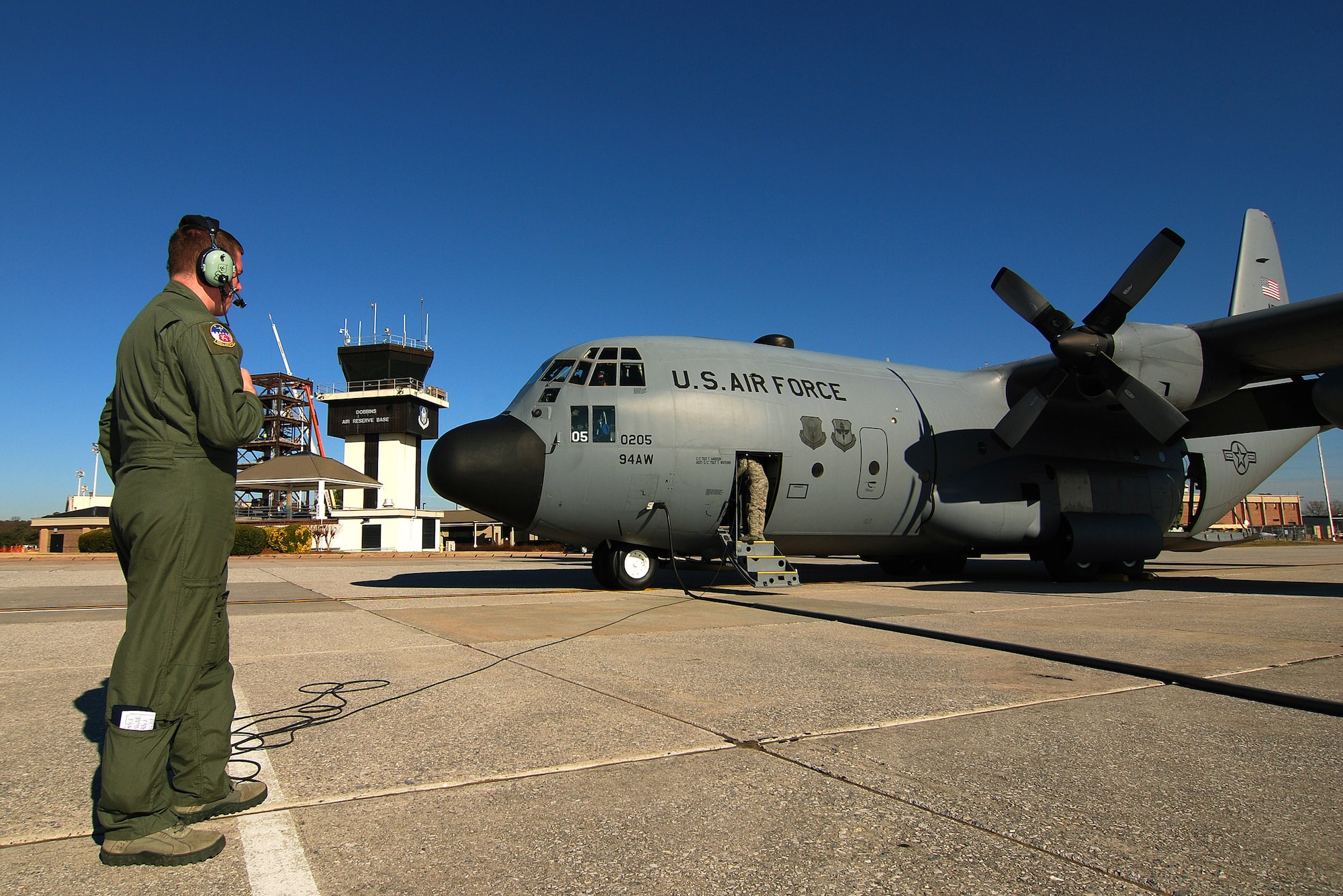 Senior Airman Brett Grove a loadmaster with the 700th Airlift Squadron communicates with the rest of the C-130H2 Hercules aircrew just prior to engines start at Dobbins Air Reserve Base, Ga., Dec 20.  Tech. Sgt. Tim Mansion of the 94th Aircraft Maintenance Flight and the dedicated crew chief for this aircraft is in the doorway talking to the second loadmaster for this mission.  (U.S. Air Force photo/ Brad Fallin)