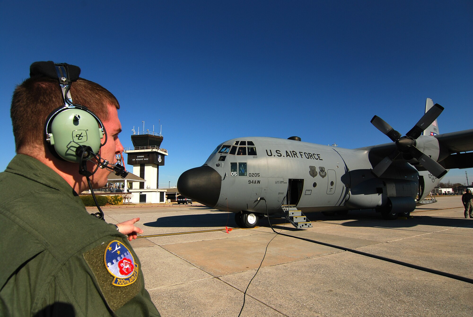 Senior Airman Brett Grove a loadmaster with the 700th Airlift Squadron communicates with the rest of the C-130H2 Hercules aircrew just prior to engines start at Dobbins Air Reserve Base, Ga., Dec 20.  Tech. Sgt. Tim Mansion of the 94th Aircraft Maintenance Flight and the dedicated crew chief for this aircraft stands by under the left wing to monitor engines start.  (U.S. Air Force photo/ Brad Fallin)