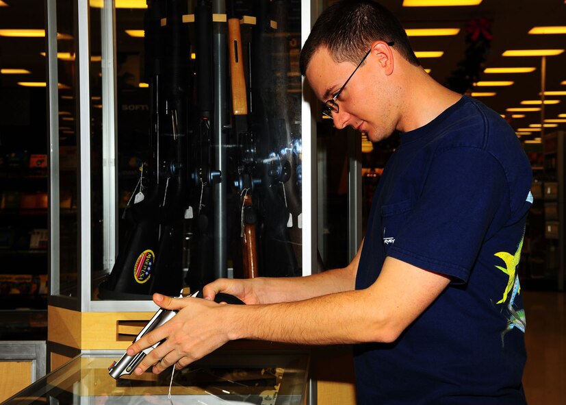 DYESS AIR FORCE BASE, Texas - Airman First Class Brian Rose, 7th Component Maintenance Squadron, looks at a pistol on Dec. 21 at the Dyess base exchange. As the Army & Air Force Exchange Service increasingly provides access to firearms and ammunition, the command has simultaneously redefined the safety measures to the sale of this merchandise, to include expanding the number of weapons it provides a complimentary trigger or cable lock for. (U.S. Air Force photo/Airman 1st Class Courtney Moses)