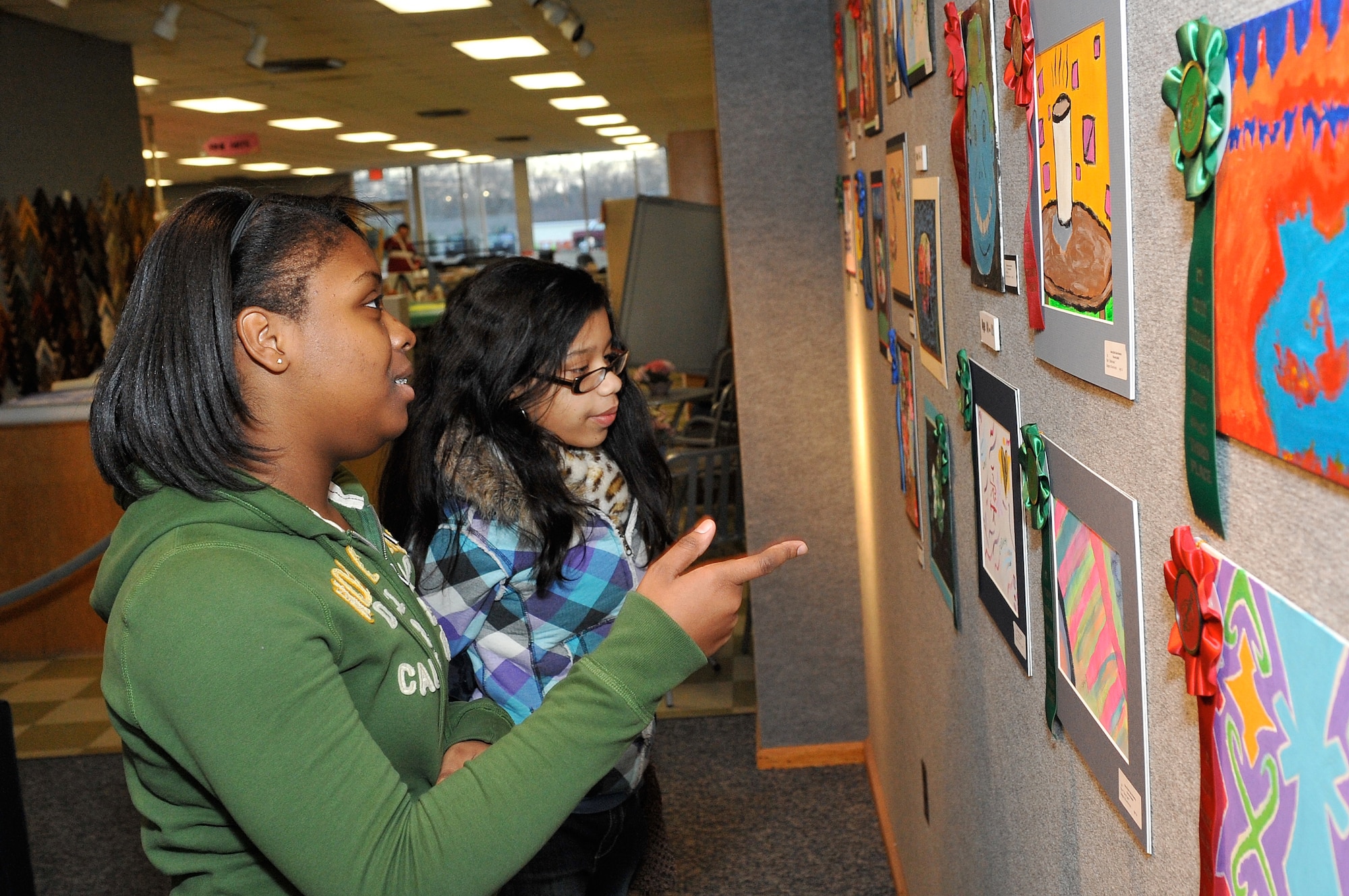 Rachel Jones, daughter of Master Sgt. (retired) Mark Jones, 305th Aerial Support Squadron, and Giselis Nieves, daughter of Jesus Nieves, 305th APS, take a look at results of the Boys and Girls Club of America Fine Arts Exhibit judging at the JB MDL Arts & Crafts Center held Dec. 14-18. Rachel took 1st Pastel and Giselis took 1st in Watercolors. (U.S. Air Force photo/Wayne Russell)