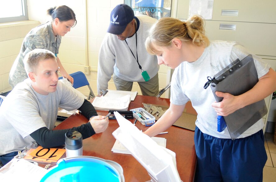 Airmen and volunteers with the 2nd Force Support Squadron converse to plan a physical training test for Airmen at the fitness center on Barksdale Air Force Base, La., Dec. 21. Upon checking in, Airmen are given a number and visit a number of stations where they get their waist measured, weight taken, number of sit-ups and push-ups within one minute counted, and a 1.5-mile run time recorded. (U.S. Air Force photo/Staff Sgt. John Gordinier)