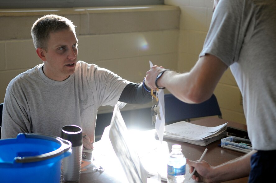 Staff Sgt. Andrew Moullette, 608th Air Operations Center combat plans division, checks in an Airman for the beginning of his physical training test at the fitness center on Barksdale Air Force Base, La., Dec. 21. Upon checking in, Airmen are given a number and visit a number of stations where they get their waist measured, weight taken, number of sit-ups and push-ups within one minute counted and a 1.5-mile run time recorded. (U.S. Air Force photo/Staff Sgt. John Gordinier)