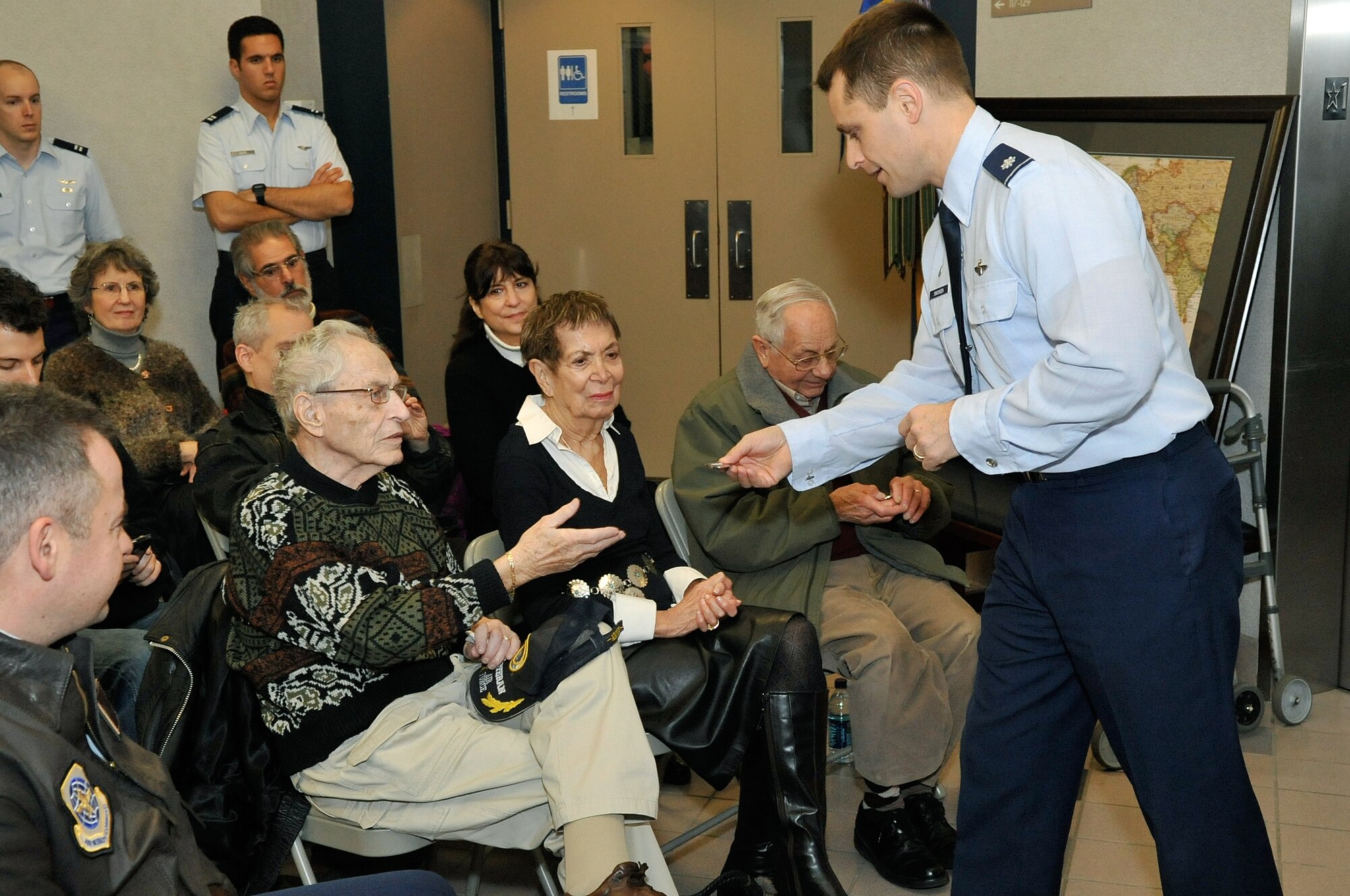 Lt. Col. Eric Simonsen, 32nd Air Refueling Squadron commander, coined Harold Schmidt, bombardier, and Dr. Sidney Gitlin, radio operator, both were aircrew members together on a bomber attached to the 32nd during WWII. Simonsen thanked them for their contributions and talked about the history of the 32nd ARS during their visit Dec. 13. (U.S. Air Force photo/Wayne Russell)