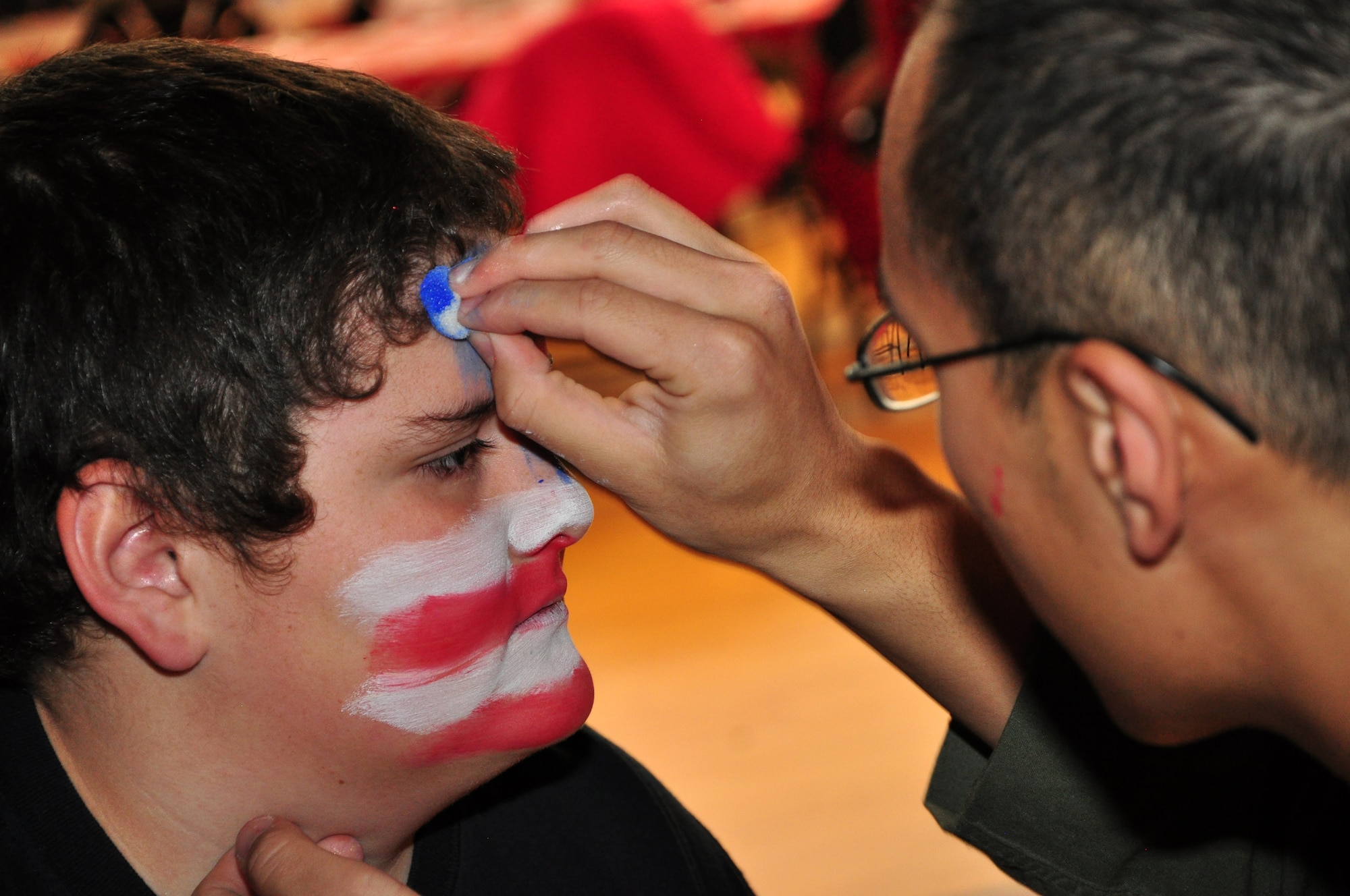 A Warren member paints an American flag on the face of one of the children from Cheyenne attending Operation Provide Joy at the Fall Hall Community Center on Dec. 11. (U.S. Air Force photo by Staff Sgt. Chad Thompson)