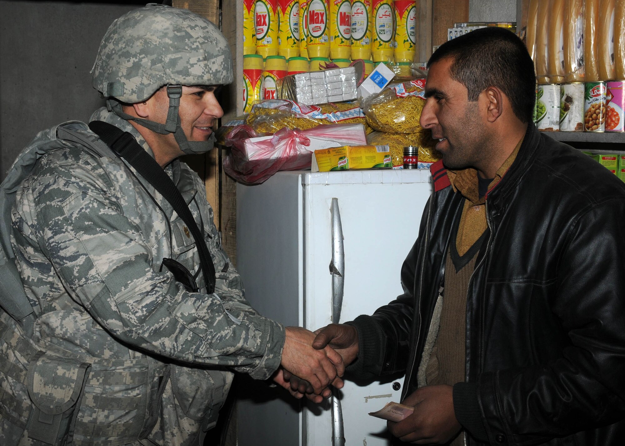 101121-N-6541W-030 KABUL, Afghanistan - Maj. David Burnett (left), the Afghan Air Force Religious and Cultural Affairs Advisor with NATO Training Command-Afghanistan, shakes hands with a shop keeper after buying beans, rice and tea that will be passed out in the coming weeks on the Afghan Air Force Base in Kabul.  (U.S. Navy photo by Mass Communication Specialist 3rd Class Jared Walker/ RELEASED).