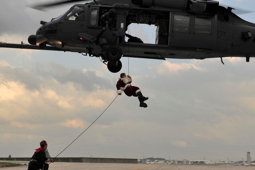 Santa Claus, with an assist from one of his elves, rappels from an HH-60 to greet children of the 31st and 33rd Rescue Squadrons at Kadena Dec 17. Santa wasn't the only attraction at this year's celebration. There were also games, bouncers, cake decorating and other events available to keep the kids entertained. (U.S. Air Force photo/Staff Sgt. Lakisha Croley)