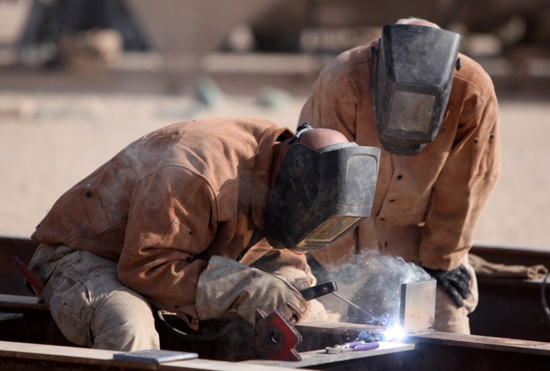 Lance Cpl. Matthew Dark, welder, Maintenance Platoon, Support Company, 8th Engineer Support Battalion, 1st Marine Logistics Group (Forward), watches as Sgt. Kenneth Cole, welder chief, welds pieces of steel during the fabrication of a non-standard bridge at Camp Leatherneck, Afghanistan, Dec. 21. The 8th ESB Marines built the bridge out of steel and wood, which will serve as a permanent replacement for a medium girder bridge in Marjah.