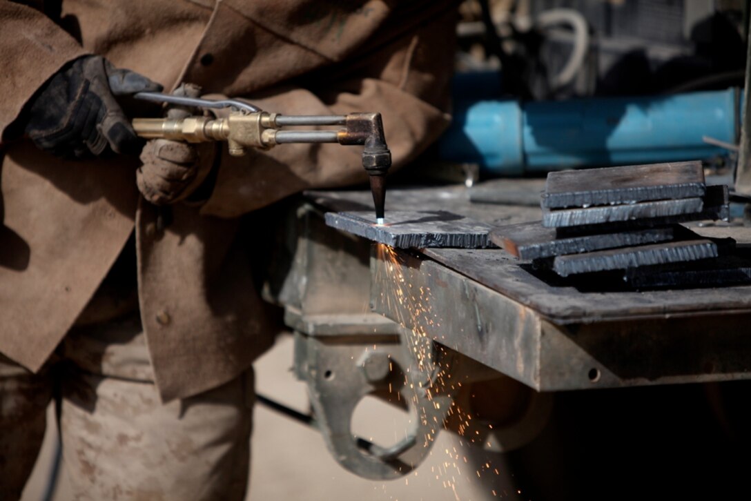A Marine with Support Company, 8th Engineer Support Battalion, 1st Marine Logistics Group (Forward), cuts pieces of steel with a cutting torch during the fabrication of a bridge at Camp Leatherneck, Afghanistan, Dec. 21. The service members with 8th ESB built the bridge out of steel and wood, which will serve as a permanent replacement for a medium girder bridge in Marjah.