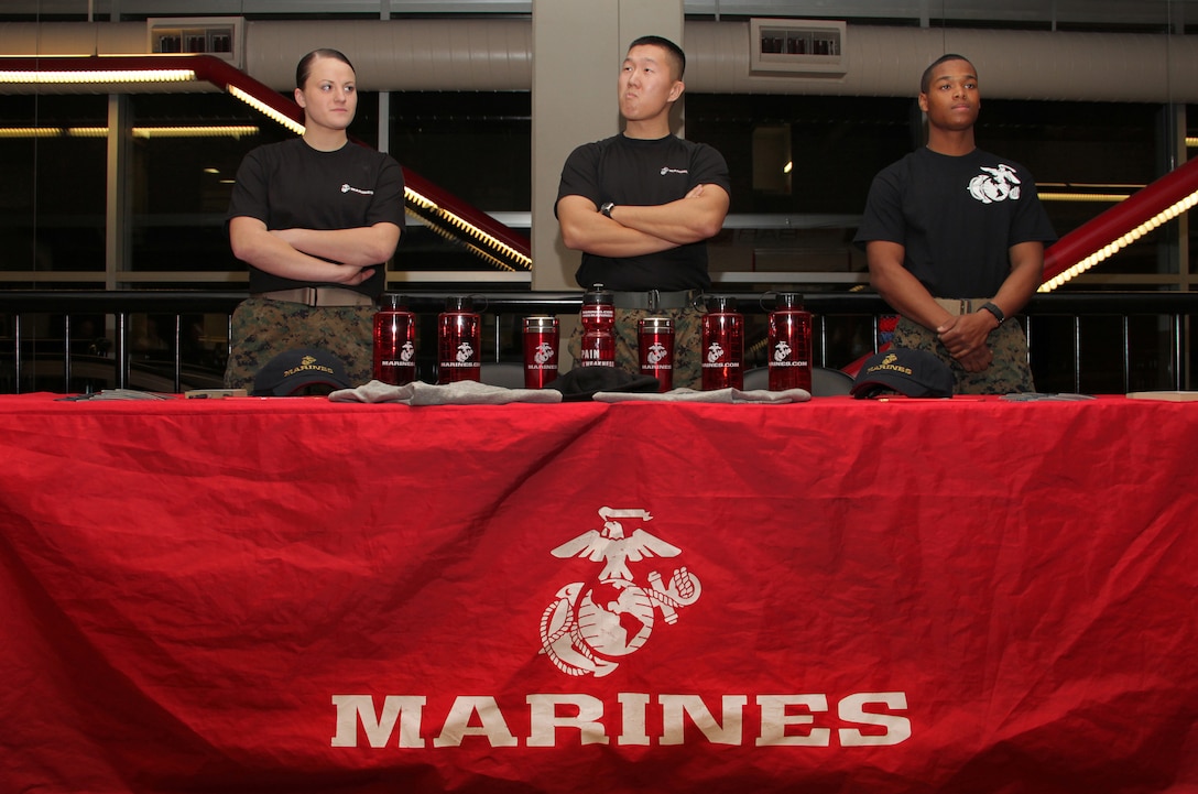 Pfc. Brittany Dexter, 19, from Blaine, Minn., Sgt. Dae Kim, 25, from Stockton, Calif., and Pvt. Nicholas Thomas, 20, from White Bear Lake, Minn., scan for individuals to take the pull-up or flexed-arm hang challenge at the Target Center Dec. 22 where the Minnesota Timberwolves took on the Utah Jazz. Dexter and Thomas recently completed Marine Corps boot camp and are currently serving at the Coon Rapids and Woodbury recruiting substations.