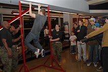 Coon Rapids, Minn., Recruiter Sgt. Aaron Swan, 30, Pvt. Nicholas Thomas, 20, currently serving as a recruiter's assistant at Woodbury, Minn., and Pfc. Brittany Dexter, 19, currently serving as a recruiter's assistant at Coon Rapids, Minn., steady the bar while a basketball fan attempts to master the Marine Corps pull-up challenge at the Target Center Dec. 22. To master the challenge, participants must perform 20 pull-ups or hang on the bar for 70 seconds.