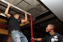 Pfc. Angelo Aguirne, 23, Marine Wing Support Squadron 471, shows his friends how to master the Marine Corps pull-up challenge at the Target Center Dec. 22 while Pvt. Nicholas Thomas, 20, currently serving as a recruiter's assistant in Woodbury, Minn., steadies the bar. Aguirne is a Newport, Minn., native.