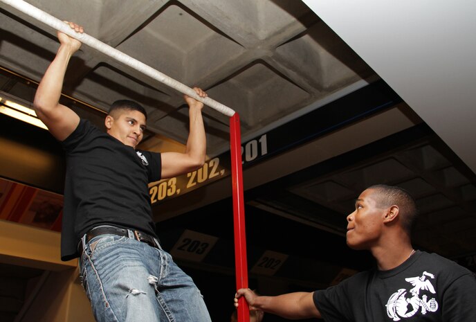 Pfc. Angelo Aguirne, 23, Marine Wing Support Squadron 471, shows his friends how to master the Marine Corps pull-up challenge at the Target Center Dec. 22 while Pvt. Nicholas Thomas, 20, currently serving as a recruiter's assistant in Woodbury, Minn., steadies the bar. Aguirne is a Newport, Minn., native.