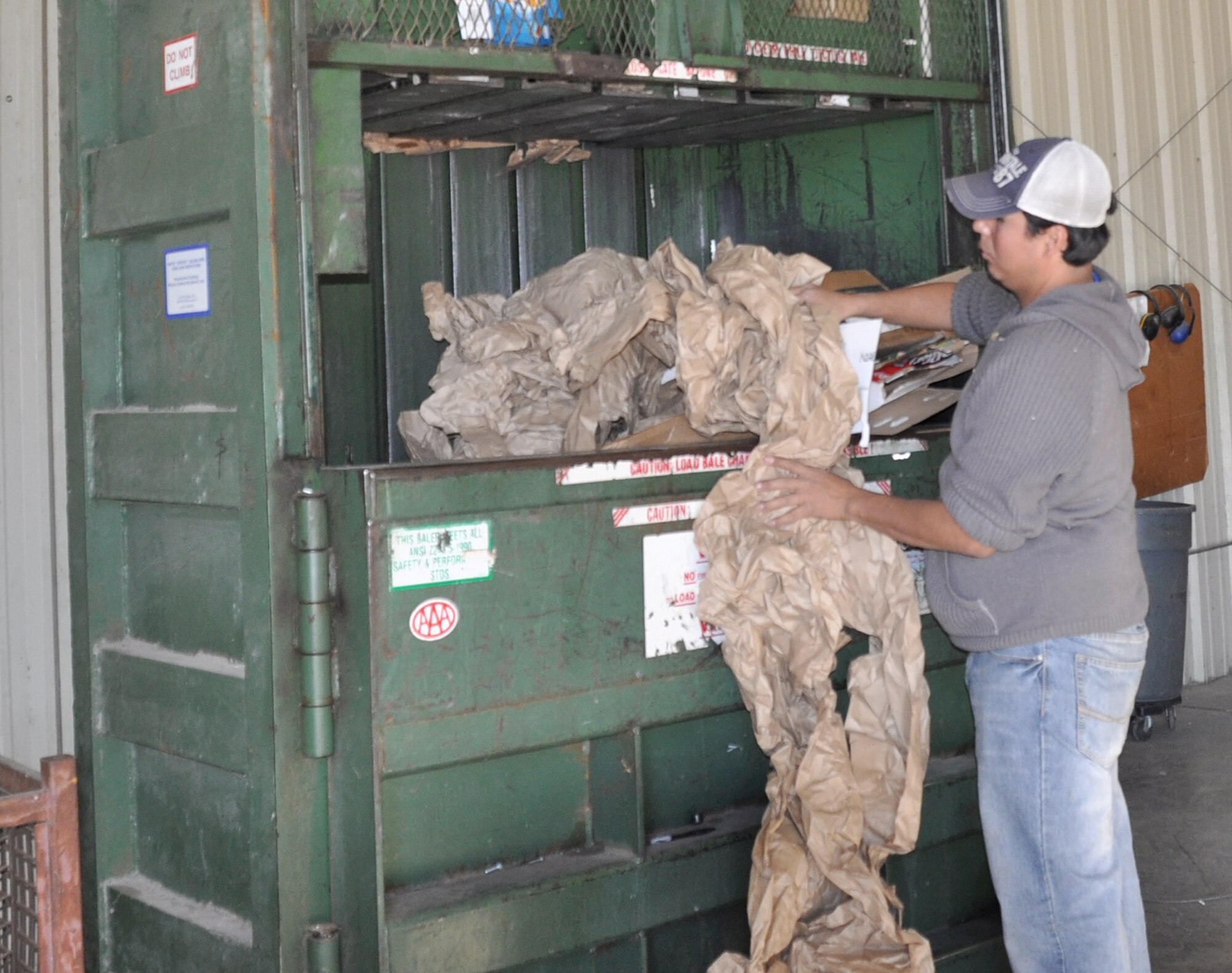 Rolando Deleon, a recycling center associate at Laughlin Air Force Base, Texas, puts paper into one of the center's five balers. The baler then compresses the material into a 1,000 to 1,200 pound bale, which is then transported to San Antonio for recycling. (U.S. Air Force photo by 2nd Lt. Angela Martin)