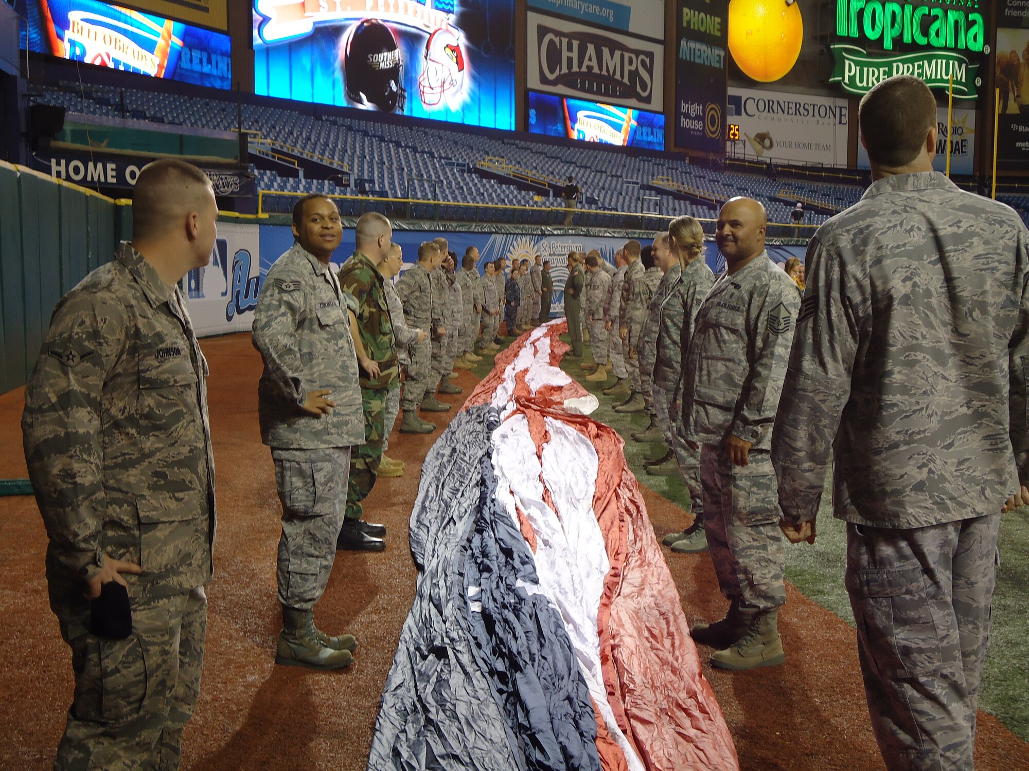Military members from MacDill await instruction during a practice run to unfold a giant U.S. flag during the opening ceremonies of the Beef O' Brady's college football bowl game. (U.S. Air Force photo by Capt. Shane Huff)