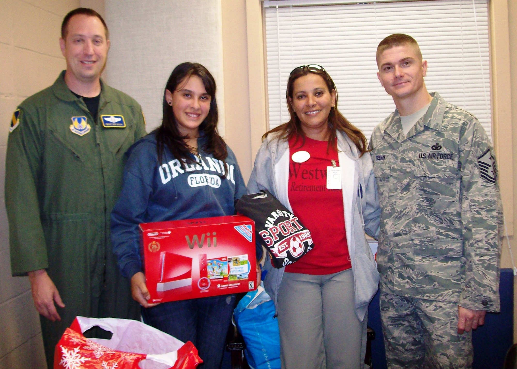 Chief Master Sgt. Robert Boyer and Master Sgt. George Freeman from the 46th Operations Group present a WII game system to an Adopt-a-Family recipient from Bruner Middle School, Fort Walton Beach, Fla. The group answered a call from Eglin Fire and Emergency Services to help the firefighters support needy families during the holidays and collected enough gifts for four families. (Courtesy photo)