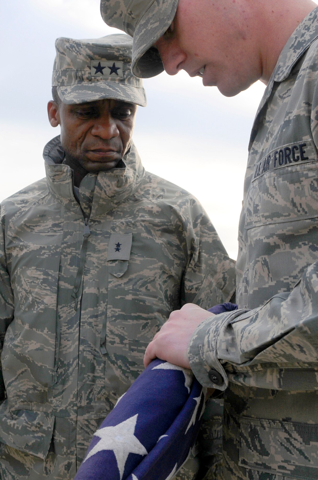 Maj. Gen. Darren McDew, Air Force District of Washington commander, listens to Airman 1st Class Robert Matthews, AFDW ceremonial guardsman, describe the precision put into every American flag folded by honor guard members, Dec. 21, on Joint Base Anacostia-Bolling. General McDew visited fellow 11th Operations Group and AFDW Airmen for his first time as commander and later coined Airman Matthews for his flawless description of his team members. (U.S. Air Force photo by Senior Airman Steele C. G. Britton)