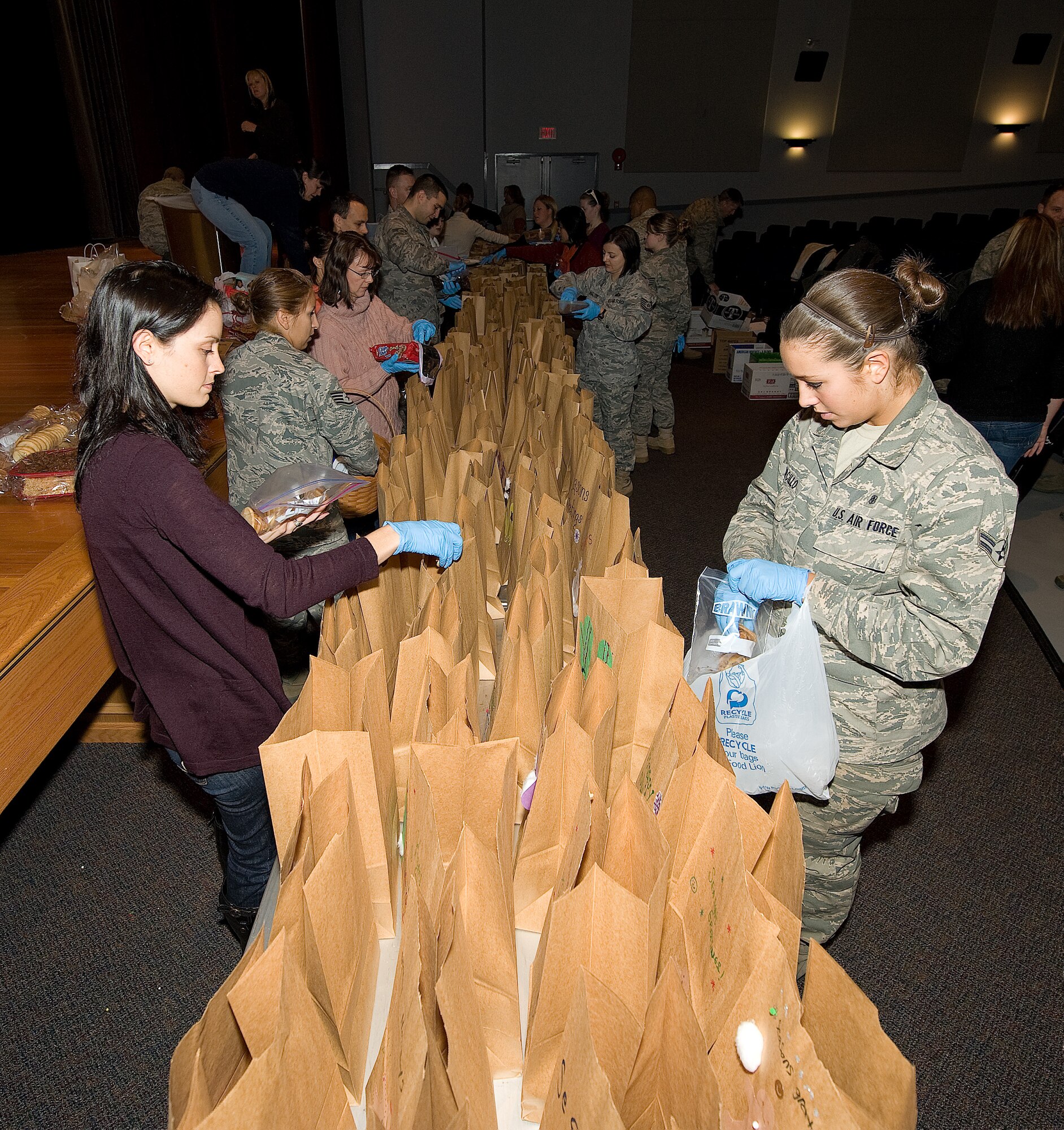 DOVER AIR FORCE BASE, Del. – Volunteers walk up and down the table placing cookies in bags at the base theater as part of Operation Cookie Drop Dec. 21, 2010. Operation Cookie Drop is an event hosted annually by Dover’s Chief’s Group.  More than 500 Airmen benefited from the operation. (U.S. Air Force photo/Jason Minto)