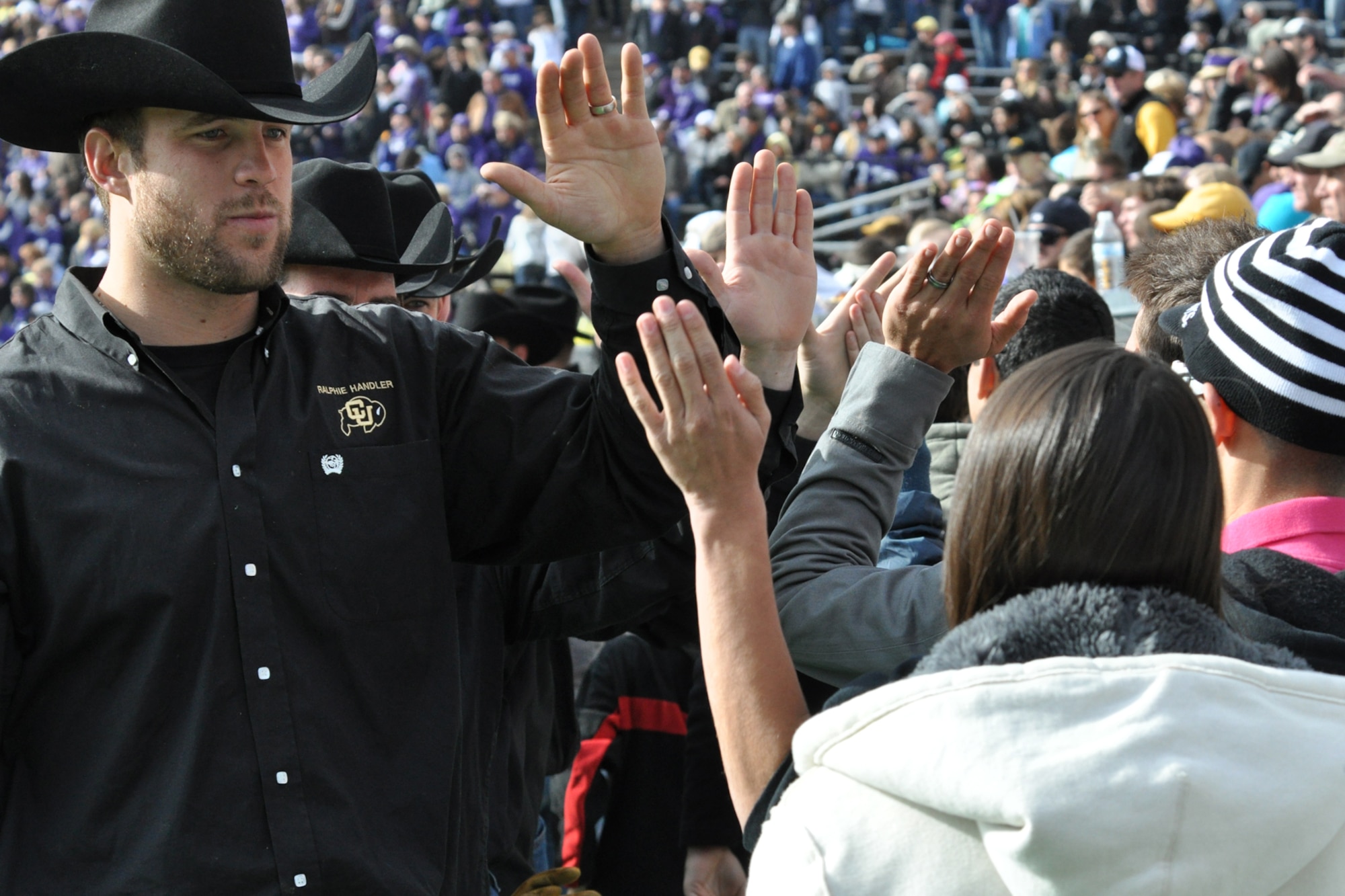Sean Tufts, a Ralphie Handler at the University of Colorado, high fives a group of kids during a break in the CU - Kansas State University football game at Folsom Field in Boulder, Colo., Nov. 20, 2010. Tufts is one of 14 handlers who take care of Ralphie, a live buffalo, that is one of the more unique mascots in all of intercollegiate athletics. She leads the football team out on the field both at the start of the game and second half. It was in the final game of the 1934 season, when a live buffalo made its first appearance when a group of students paid $25 to rent a buffalo calf along with a real cowboy as his keeper. It took the cowboy and four students to keep the calf under control on the sidelines during the 7-0 win at the University of Denver on Thanksgiving Day. (Courtesy photo/Jeff Walston)  