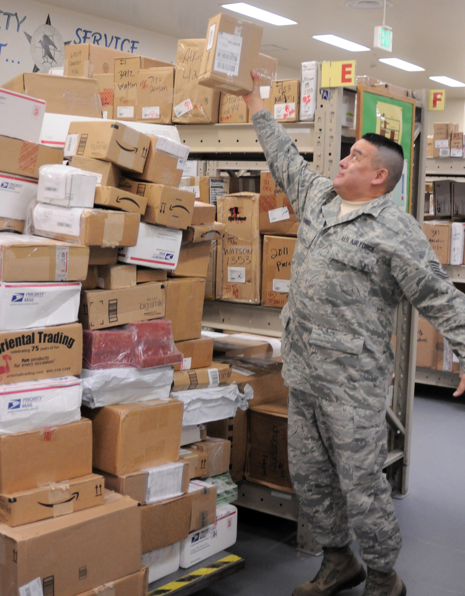 YOKOTA AIR BASE, Japan -- Tech. Sgt. Mario Rangel, NCO in charge of postal operations, reaches for a box of of the top of a mountain of mail inside the Post Office here Dec. 17. The Yokota Post Office relies on volunteers to help sort through thousends of boxes and letters during the holiday.(U.S. Air Force photo/ 2nd Lt. Christopher Love )