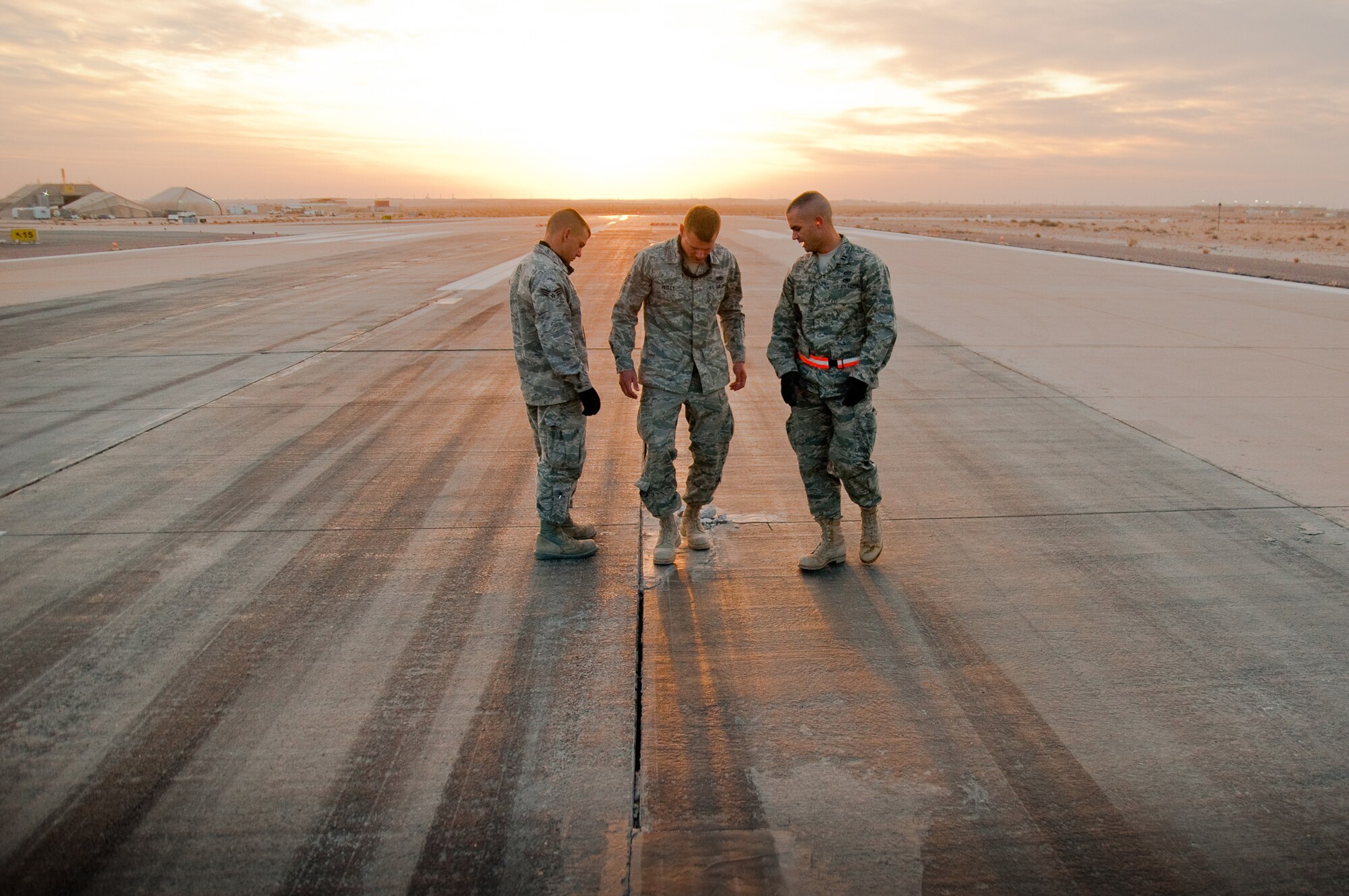 SOUTHWEST ASIA - Members of the 386th Expeditionary Civil Engineer Squadron's Runway Repair Team examine cracked pavement Dec. 10, 2010, on a runway at the 386th Air Expeditionary Wing. The team has poured more than 180 cubic feet of fresh mortar in the past six months to repair crumbling concrete. (U.S. Air Force photo by Maj. Dale Greer)