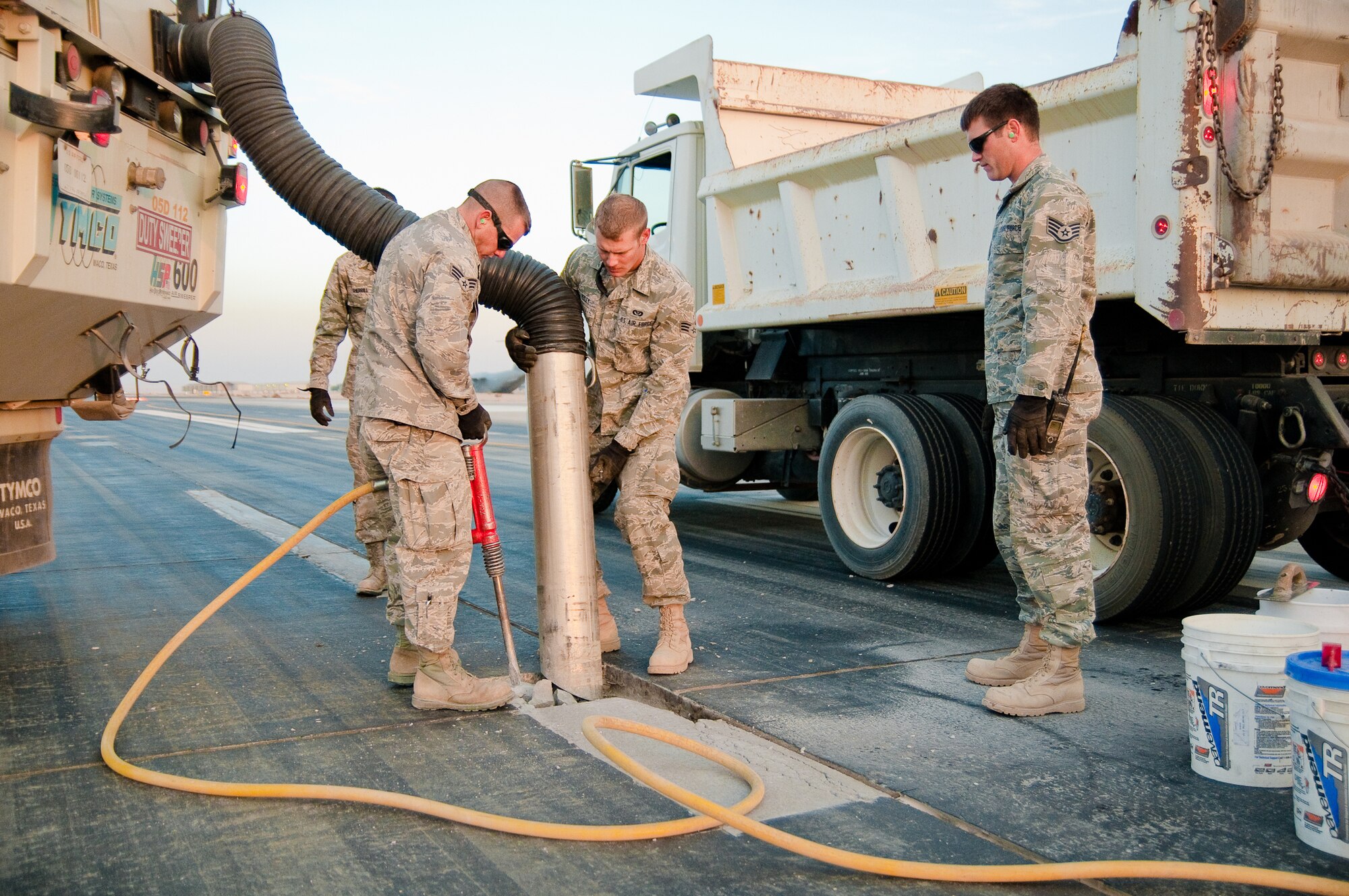 SOUTHWEST ASIA - Members of the 386th Expeditionary Civil Engineer Squadron's Runway Repair Team excavate cracked pavement and remove debris with a sweeper truck Dec. 10, 2010, on a runway at the 386th Air Expeditionary Wing. The team makes weekly repairs to the runways at an undisclosed air base here. (U.S. Air Force by photo Maj. Dale Greer)