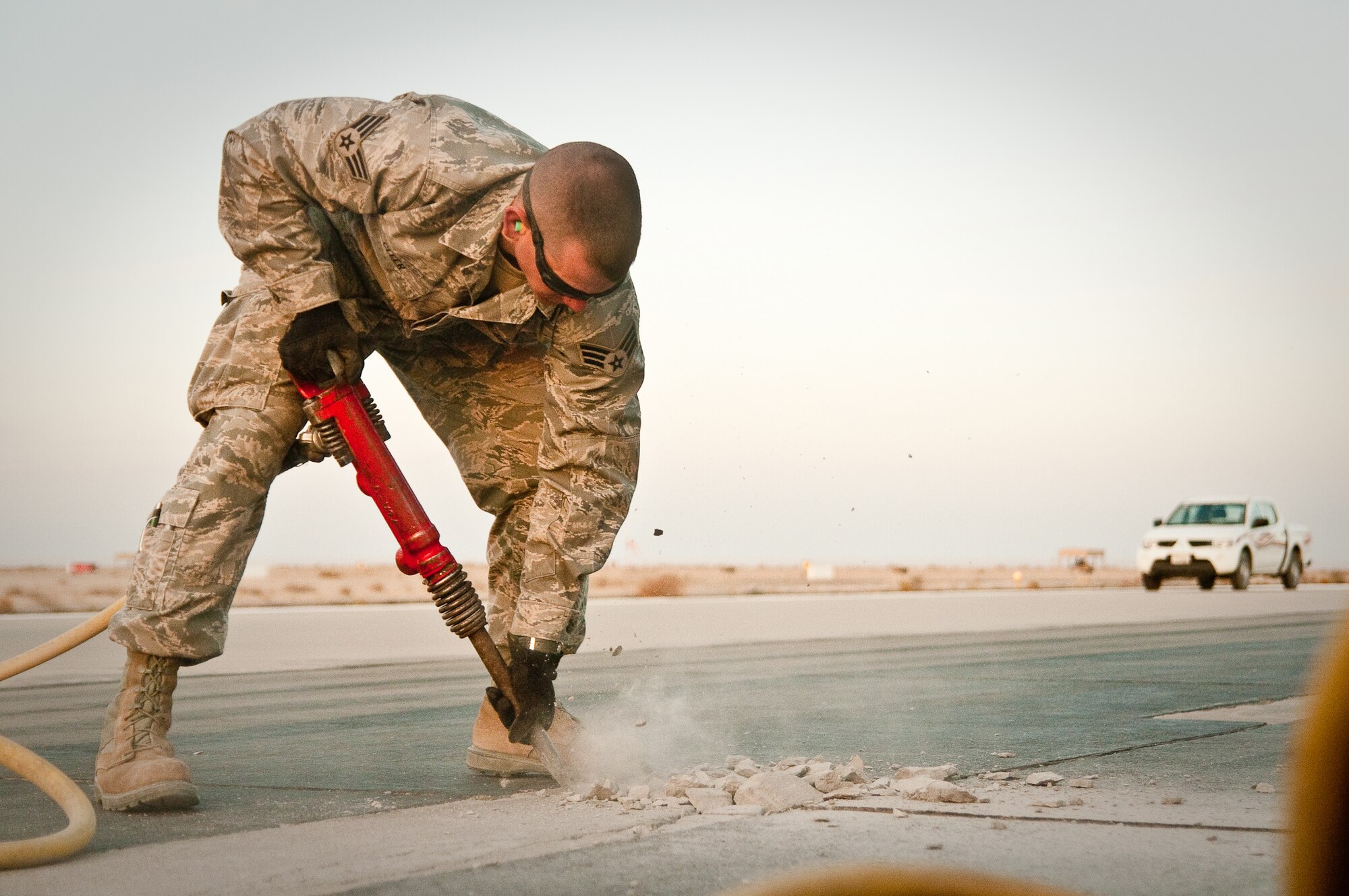 SOUTHWEST ASIA - Senior Airman Jacob Cleer, a heavy equipment operator assigned to the 386th Expeditionary Civil Engineer Squadron, pulverizes a section damaged runway pavement with a jackhammer at an undisclosed air base here Dec. 10, 2010. Airman Cleer's coworkers will collect the bits of excavated concrete with a sweeper truck before filling the cavity with fresh mortar. The squadron conducts weekly runway repairs to prevent damage to aircraft from foreign object debris, or FOD. (U.S. Air Force photo by Maj. Dale Greer)