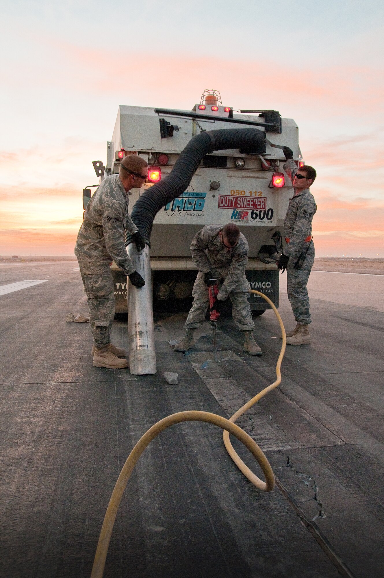 SOUTHWEST ASIA - Members of the 386th Expeditionary Civil Engineer Squadron's Runway Repair Team excavate cracked pavement and remove debris with a sweeper truck Dec. 10, 2010, on a runway at the 386th Air Expeditionary Wing. The team makes weekly repairs to the runways at an undisclosed air base here. (U.S. Air Force photo by Maj. Dale Greer)
