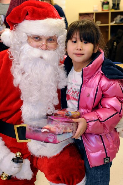 Santa Claus poses with Mya WarBonnett, 5, at the Youth & Family Services Child Care program in Rapid City, S.D., Dec. 16.  Santa, Mrs. Claus and roughly 30 volunteers from the base assisted in delivering toys as part of the 28th Operations Group Angel Tree Program. (U.S. Air Force photo/Staff Sgt. Marc I. Lane)
