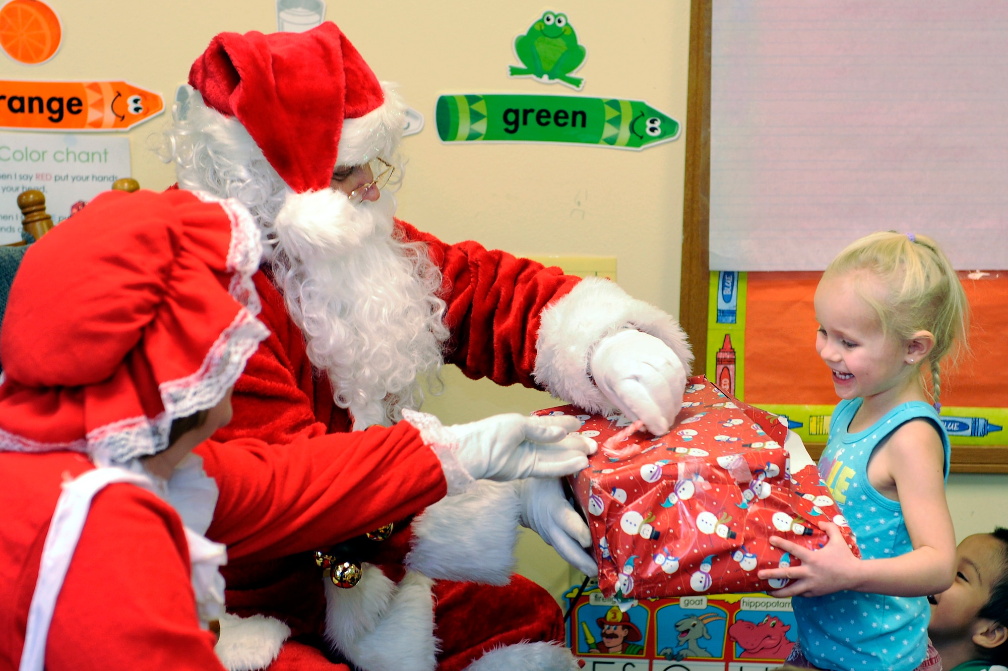 Santa Claus gives a gift to a young girl enrolled in the Youth & Family Services Child Care program in Rapid City, S.D., Dec. 16.  The gift was one of 170 donated by various organizations from Ellsworth Air Force Base, S.D. (U.S. Air Force photo/Staff Sgt. Marc I. Lane)