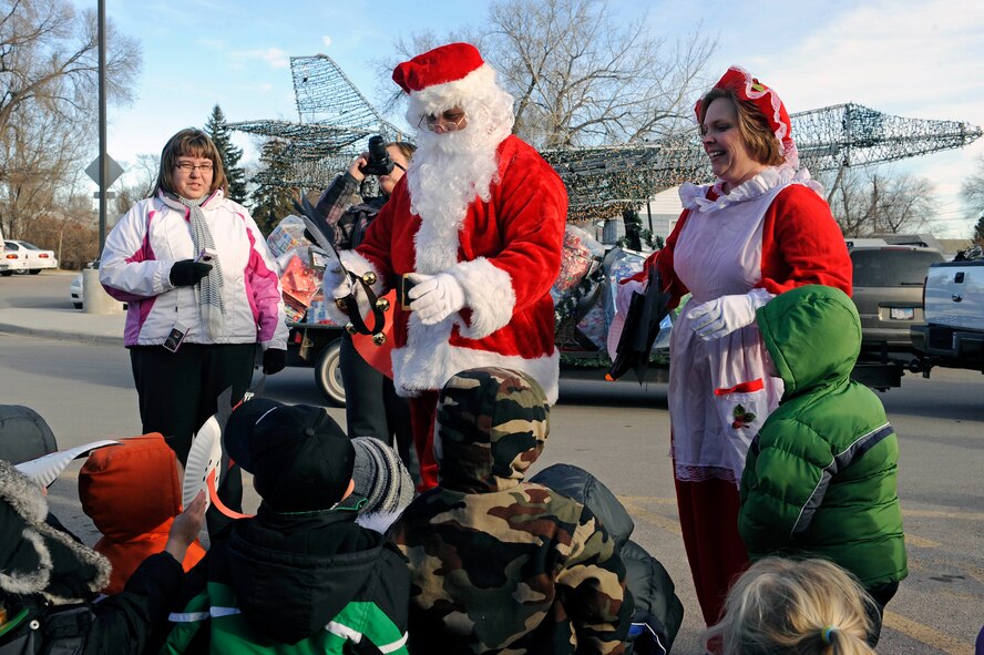 Santa and Mrs. Claus greet children enrolled in the Youth & Family Services Child Care program in Rapid City, S.D., Dec. 16.  Arriving aboard the base’s Parade of Lights float, Santa and Mrs. Claus assisted roughly 30 Airmen from the base in delivering 170 gifts to the children. (U.S. Air Force photo/Staff Sgt. Marc I. Lane)