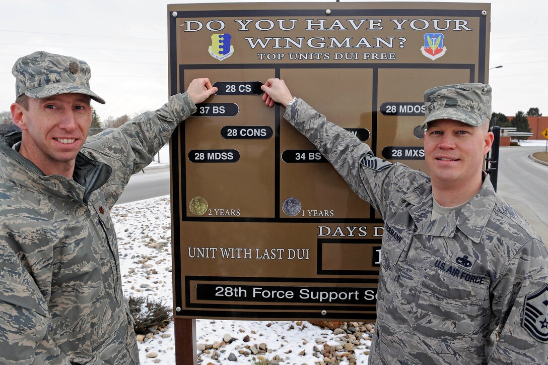 (Left) Maj. Robert Kelly, 28th Communications Squadron commander, and Master Sgt. Carl Petermann, 28 CS first sergeant, place their squadron magnet into the two years DUI free section of a sign board at Ellsworth Air Force Base, S.D., Dec. 22.  By doing their part to prevent DUIs, the 28th CS sets a good example in developing a positive culture at Ellsworth.  